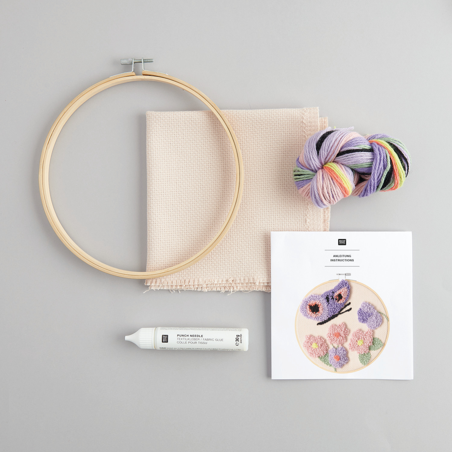 Punch Needle Packung Schmetterling von Rico Design mit Stickrahmen, Garn und Anleitung auf grauem Hintergrund.