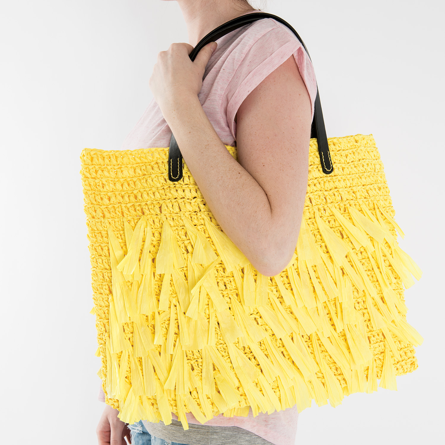 Häkelanleitung Tasche aus Creative Paper: Große gelbe Tasche mit Fransen und schwarzen Henkeln.