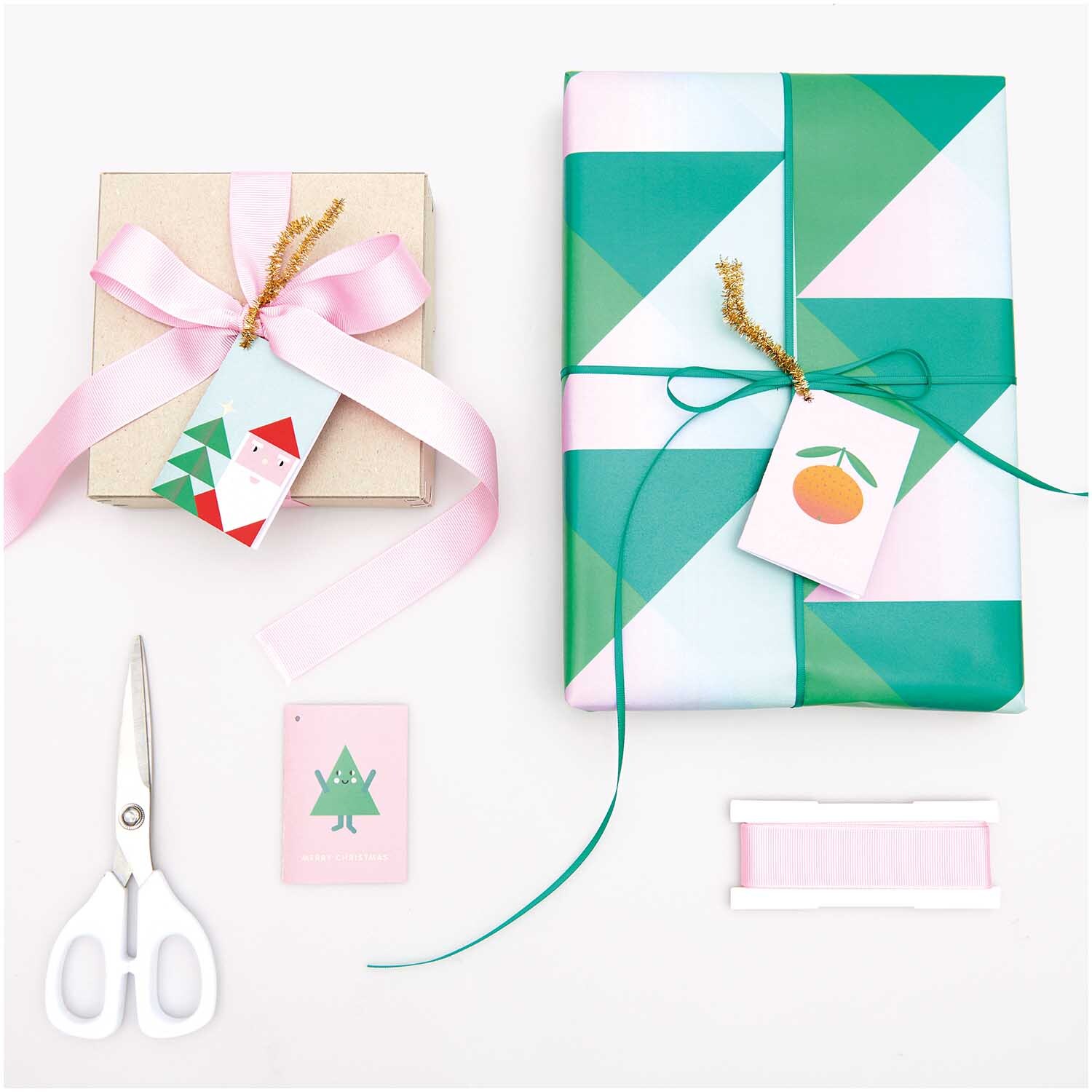 Paper Poetry Kärtchenanhänger pastell Merry Christmas 6 Stück: Geschenke mit bunten Anhängern und Schleifen, Schere und Band auf weißem Hintergrund.