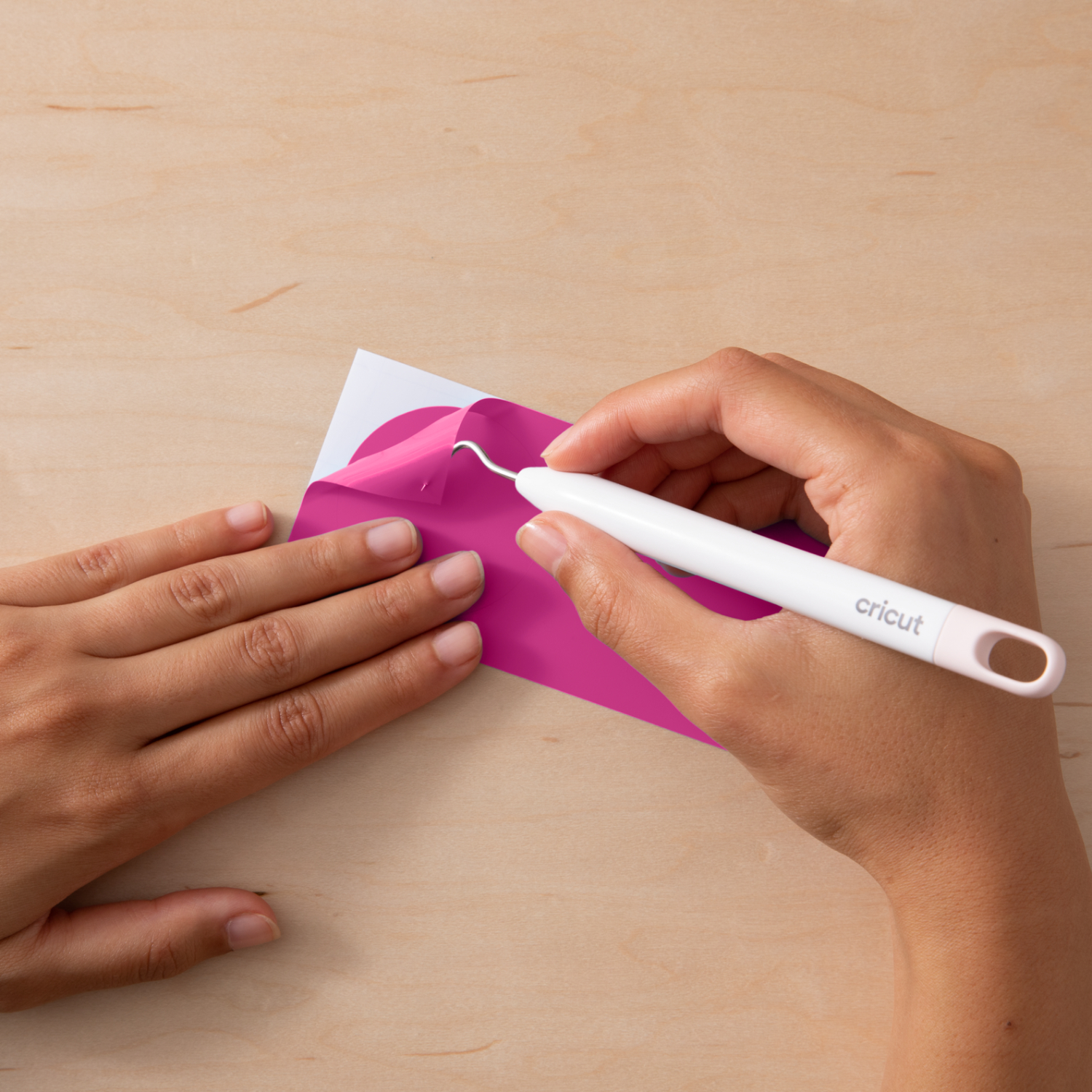 Color change Vinyl HOT Permanent: Hände verwenden ein Cricut-Werkzeug, um rosa Vinylfolie zu bearbeiten.