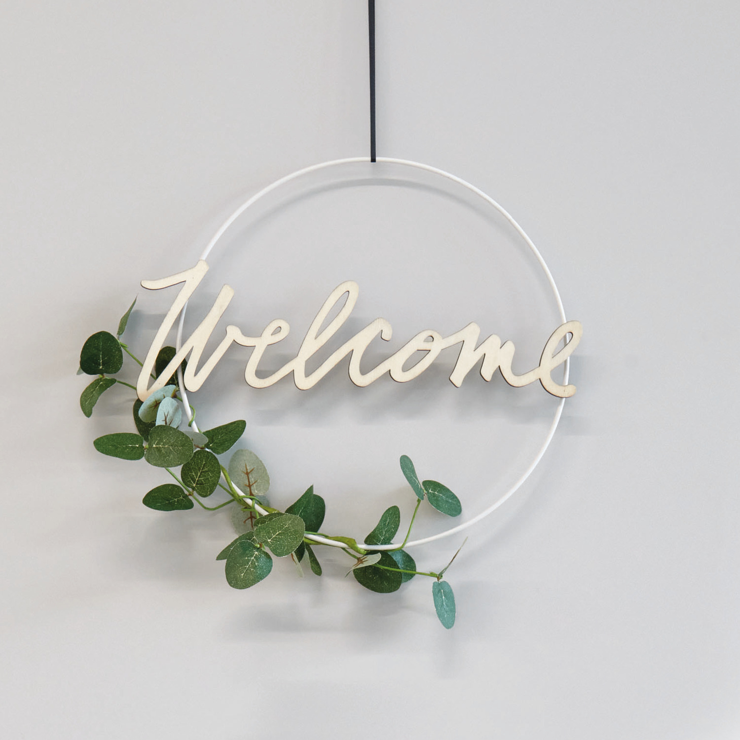 Holzschriftzug magnetisch "Welcome" 29x10cm von Rico Design, dekoriert mit grünen Blättern auf einem weißen Ring.