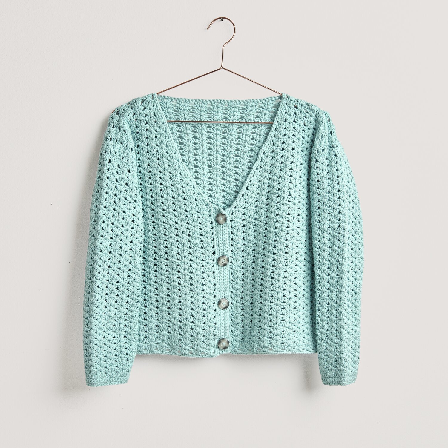 Häkelset Jacke Modell 11 aus Lovewool No. 20 in Aquamarin, präsentiert auf einem Kleiderbügel.