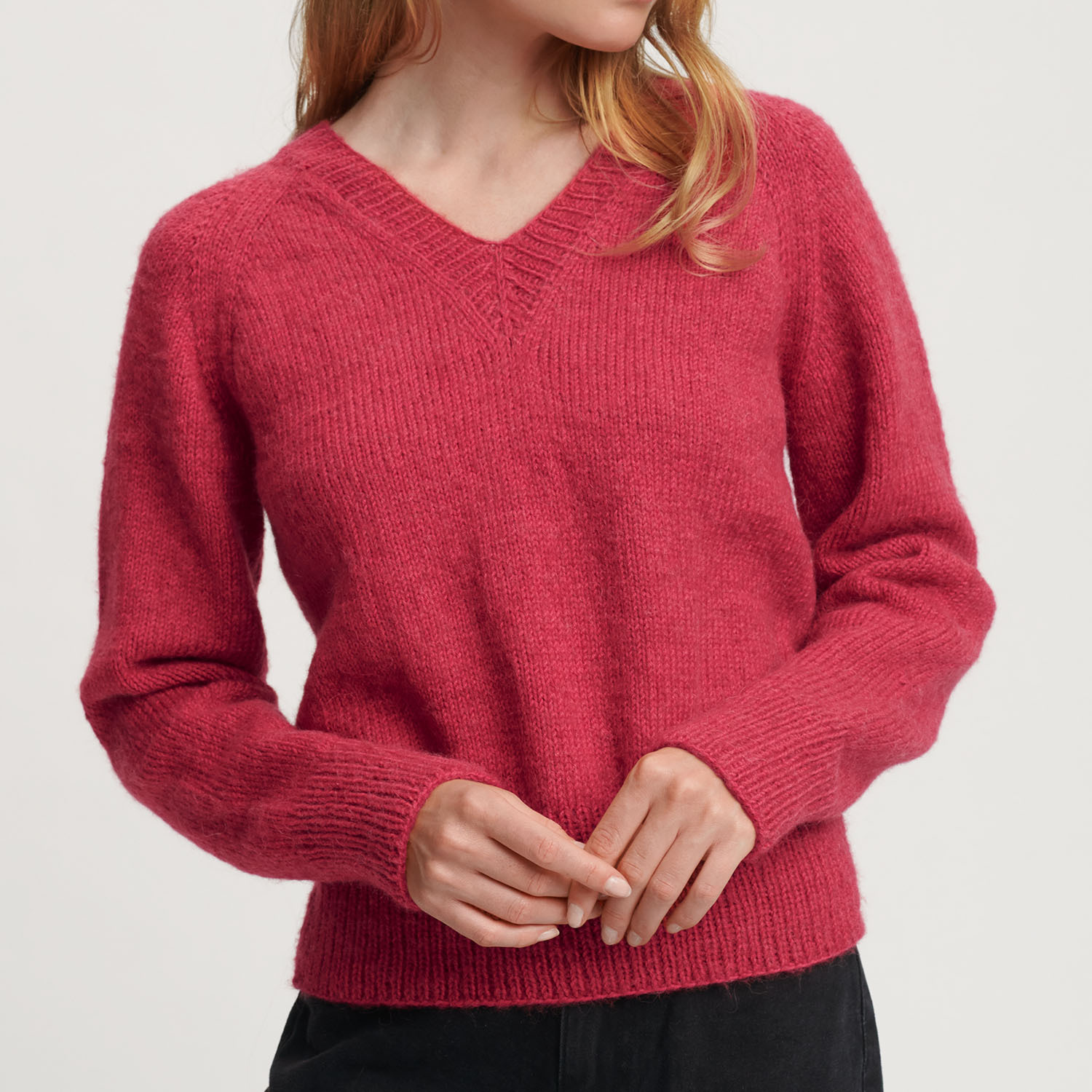Strickanleitung Pullover aus Siena & Essentials Baby Alpaca Loves Silk: Frau trägt roten V-Pullover.
