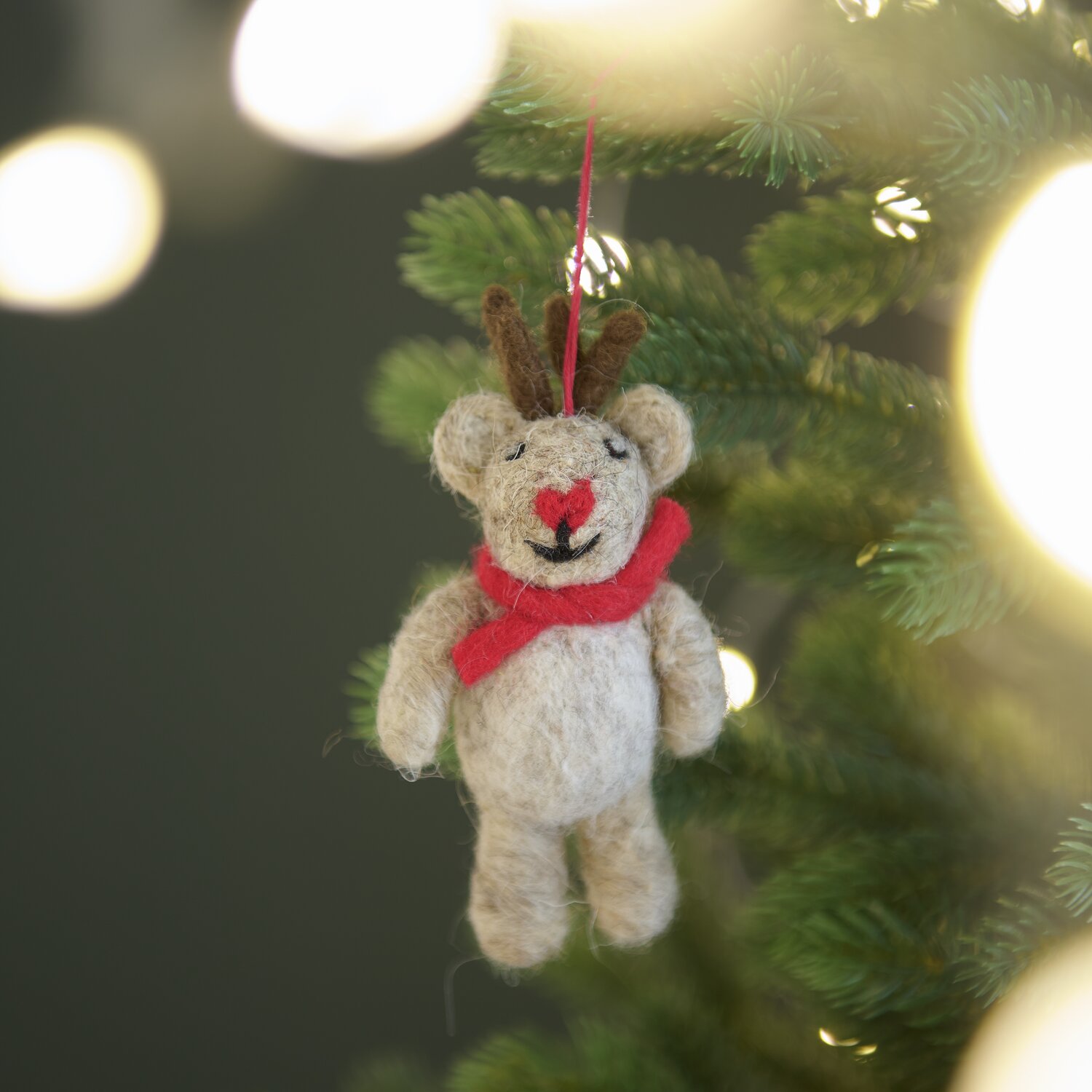 Aufhänger Filz-Hirsch Braun: Niedlicher Hirsch aus Filz mit rotem Schal, hängend an einem Weihnachtsbaum. Größe 11x6x3cm.