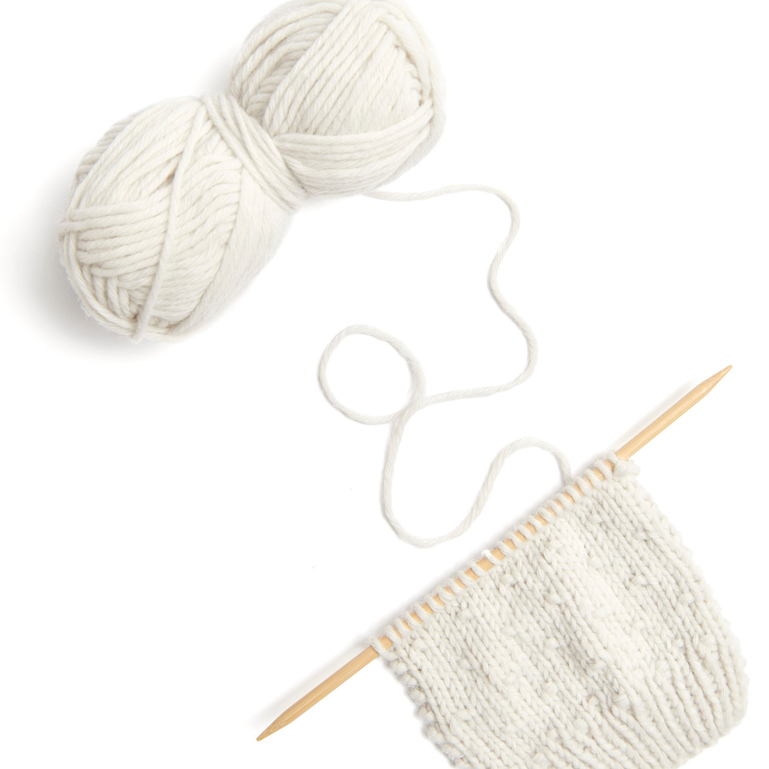 Essentials Vegan Cashmere aran: Strickprojekt mit cremefarbenem Garn von Rico Design, 50g 100m, auf Holzstricknadeln.