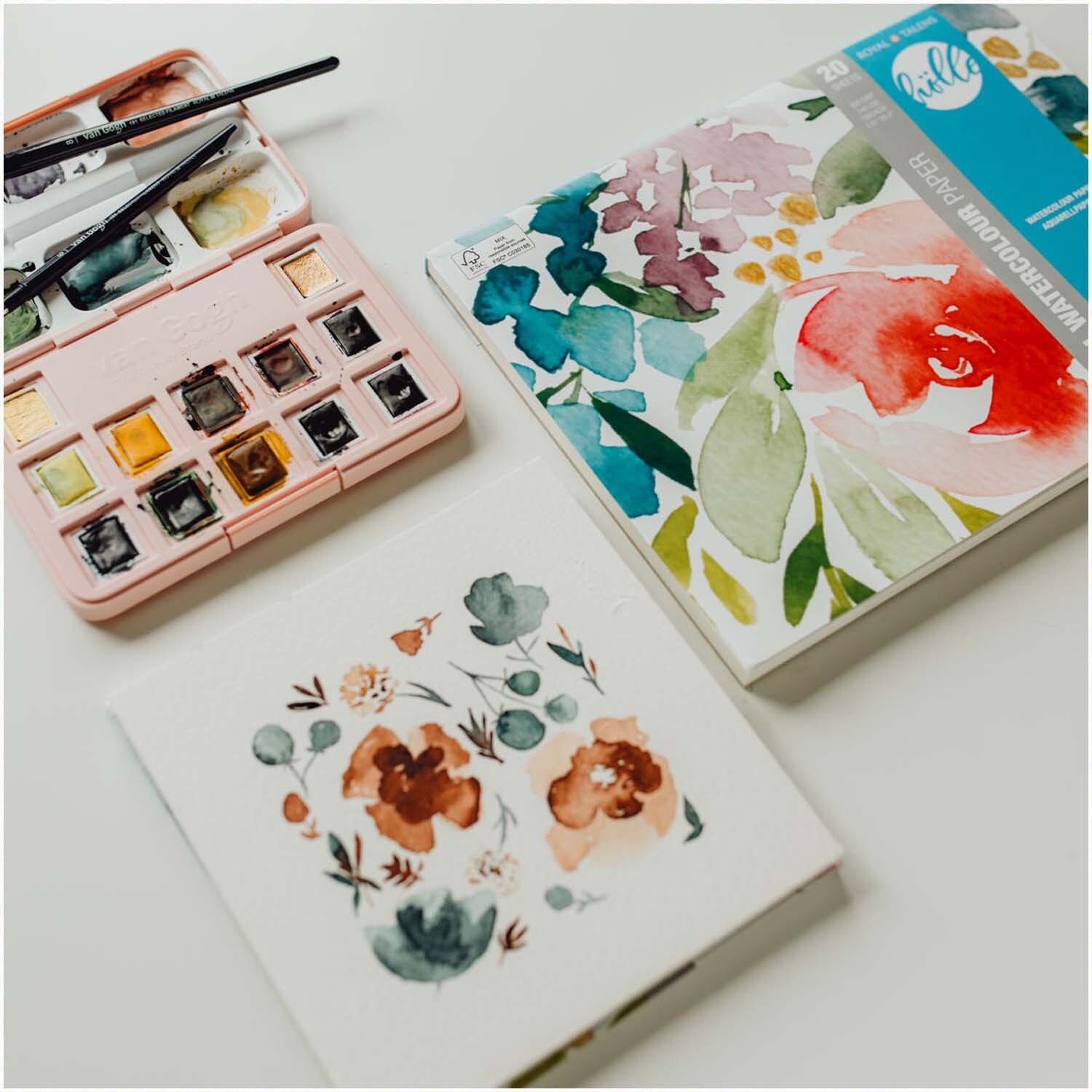 van Gogh Aquarellpapier mit floralen Mustern, Pinsel und Farben von Frau Hölle auf einem Tisch.