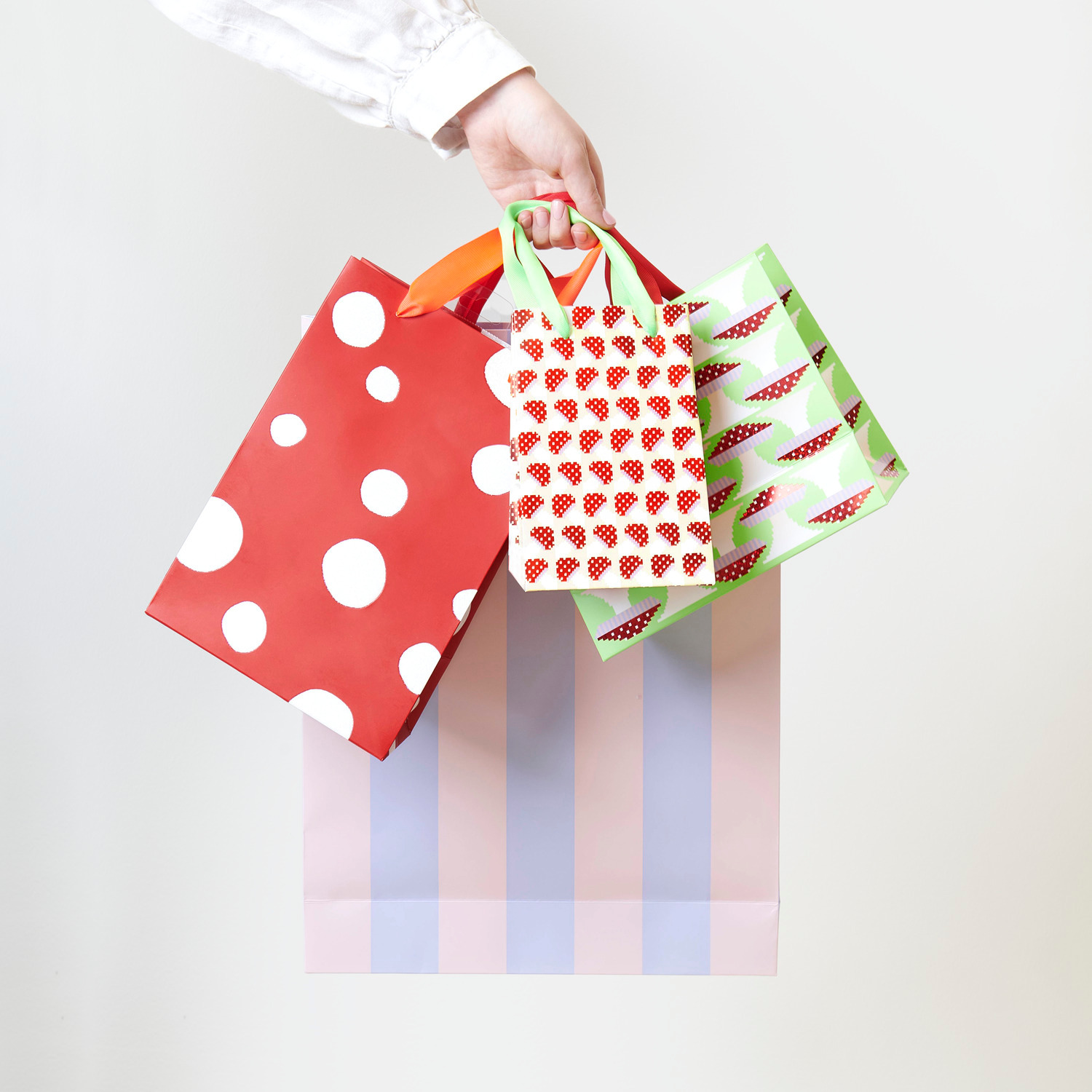 Geschenktüte Fliegenpilz Pixel Grün, gehalten von einer Hand, mit bunten Mustern und Streifen.