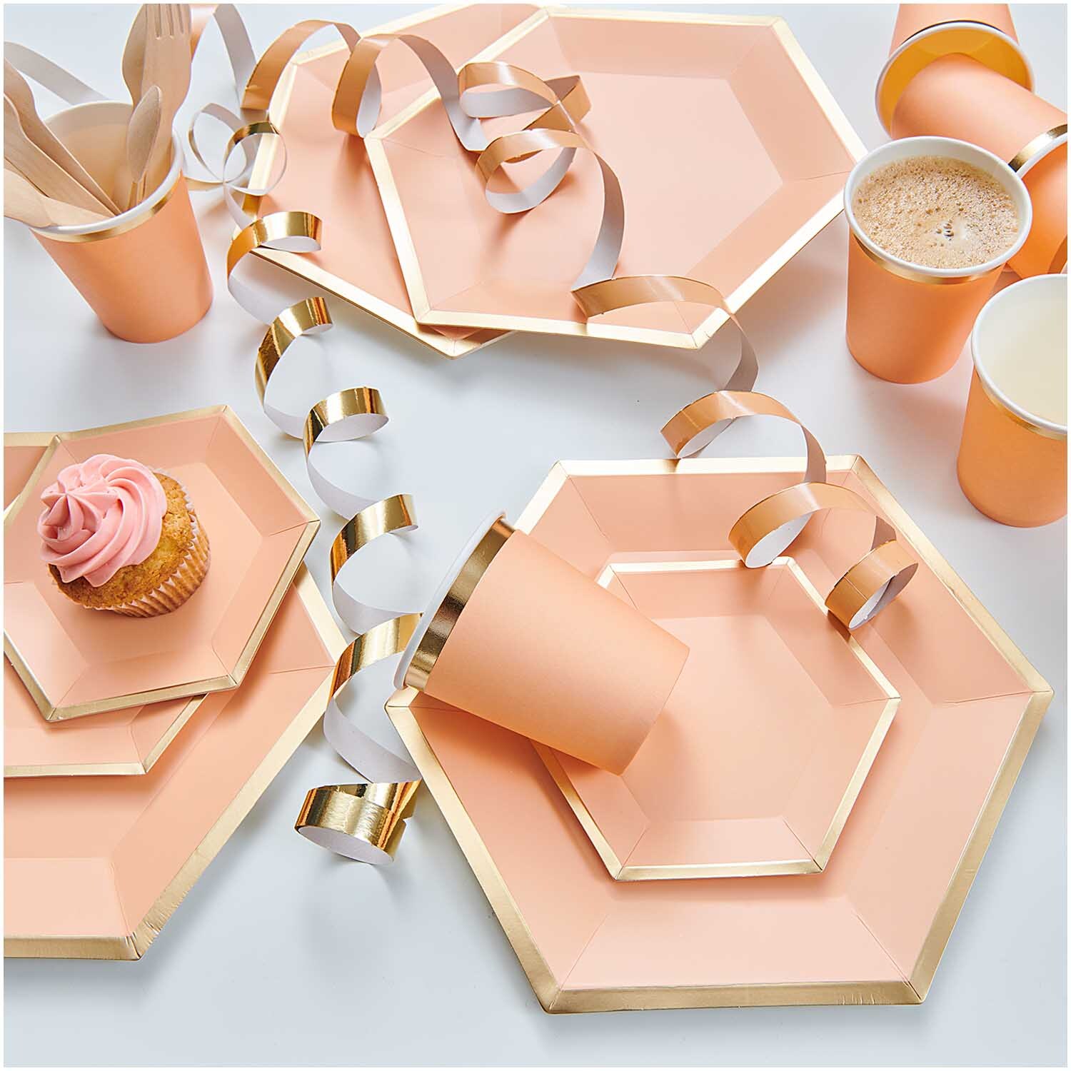 Pappteller Sechseck in Apricot-Gold von Rico Design, dekoriert mit Partyzubehör und Getränken.