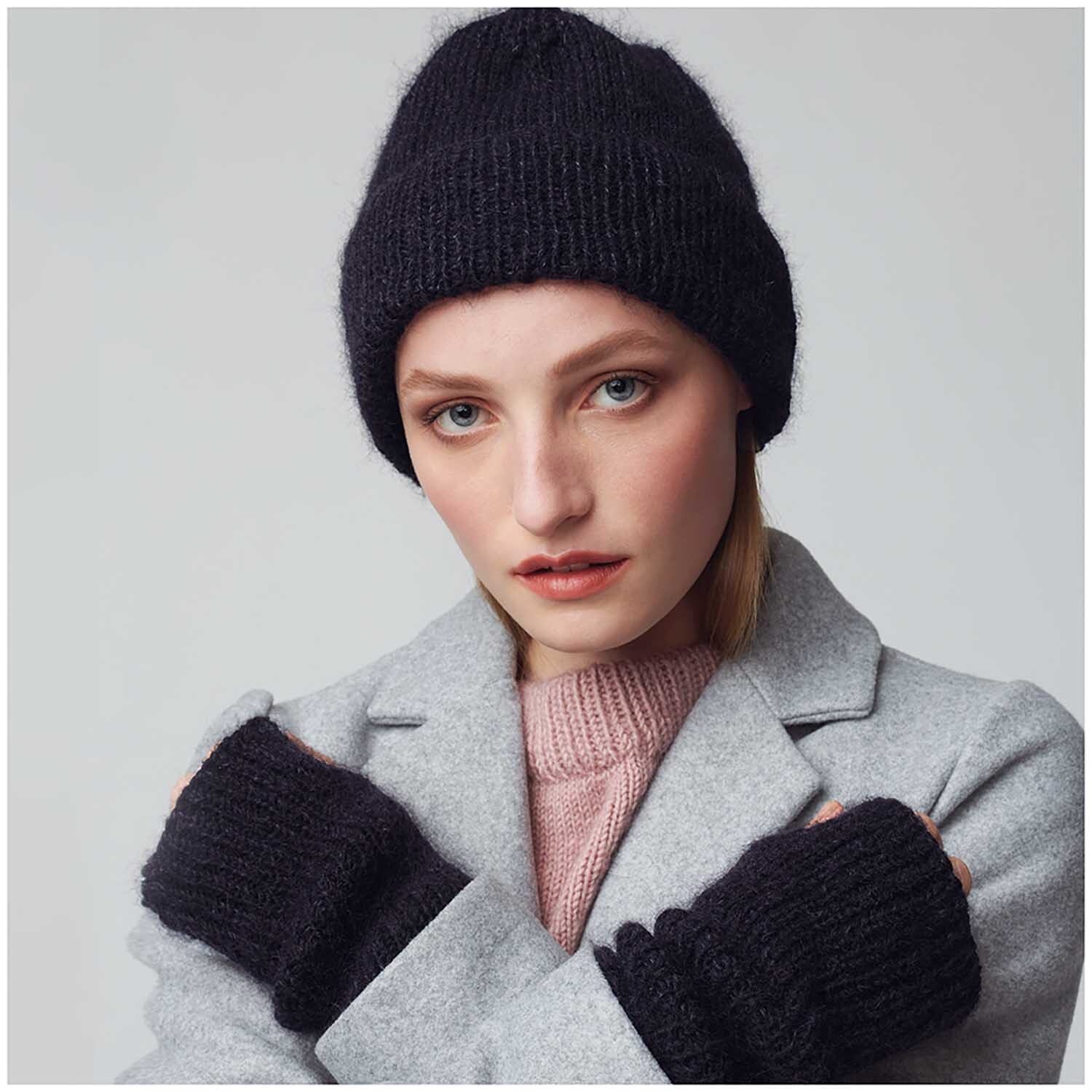Essentials Super Kid Mohair Loves Silk: Frau trägt schwarzen Hut und Handschuhe von Rico Design, passend zu grauem Mantel und rosa Pullover.