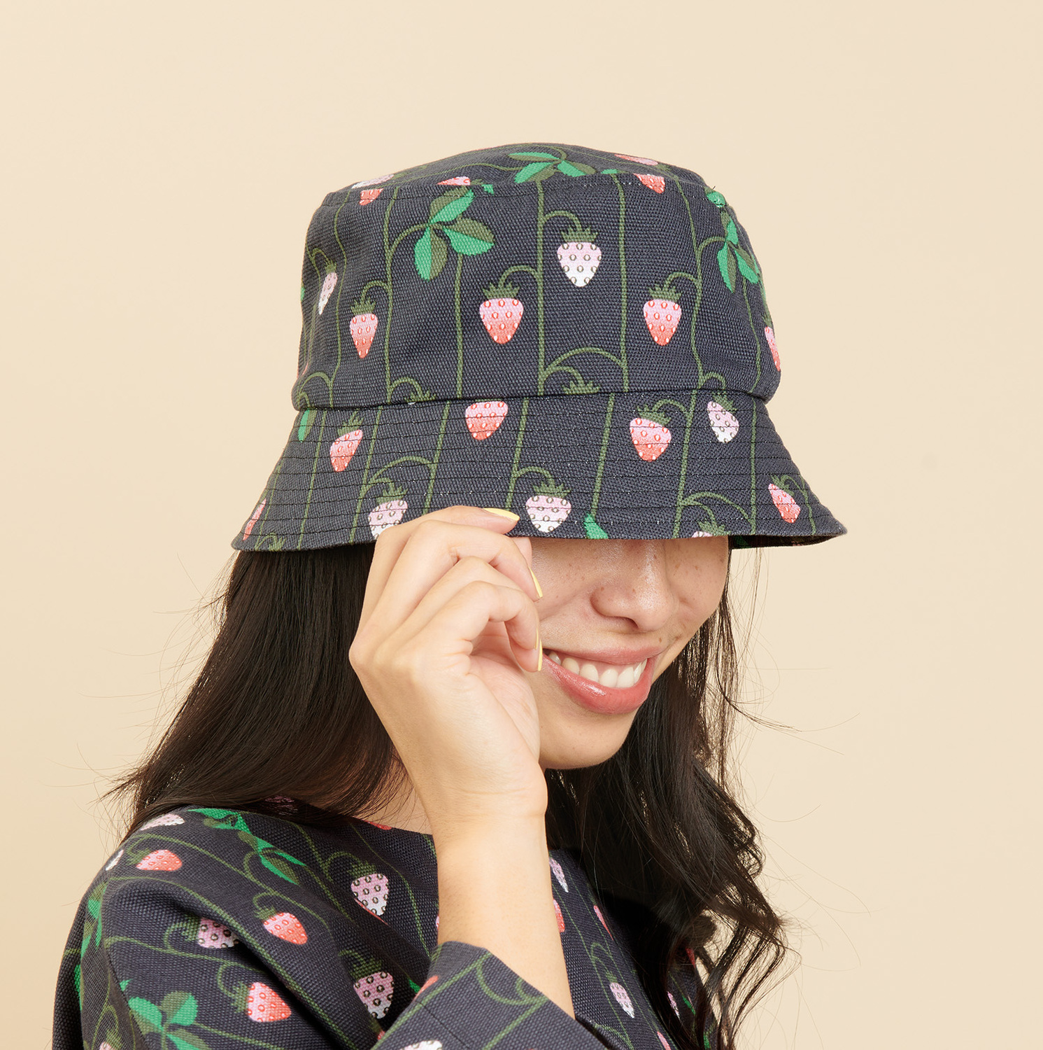 Nähanleitung Bucket Hat mit Erdbeer-Muster: Frau trägt dunkelblauen Hut mit Erdbeeren.