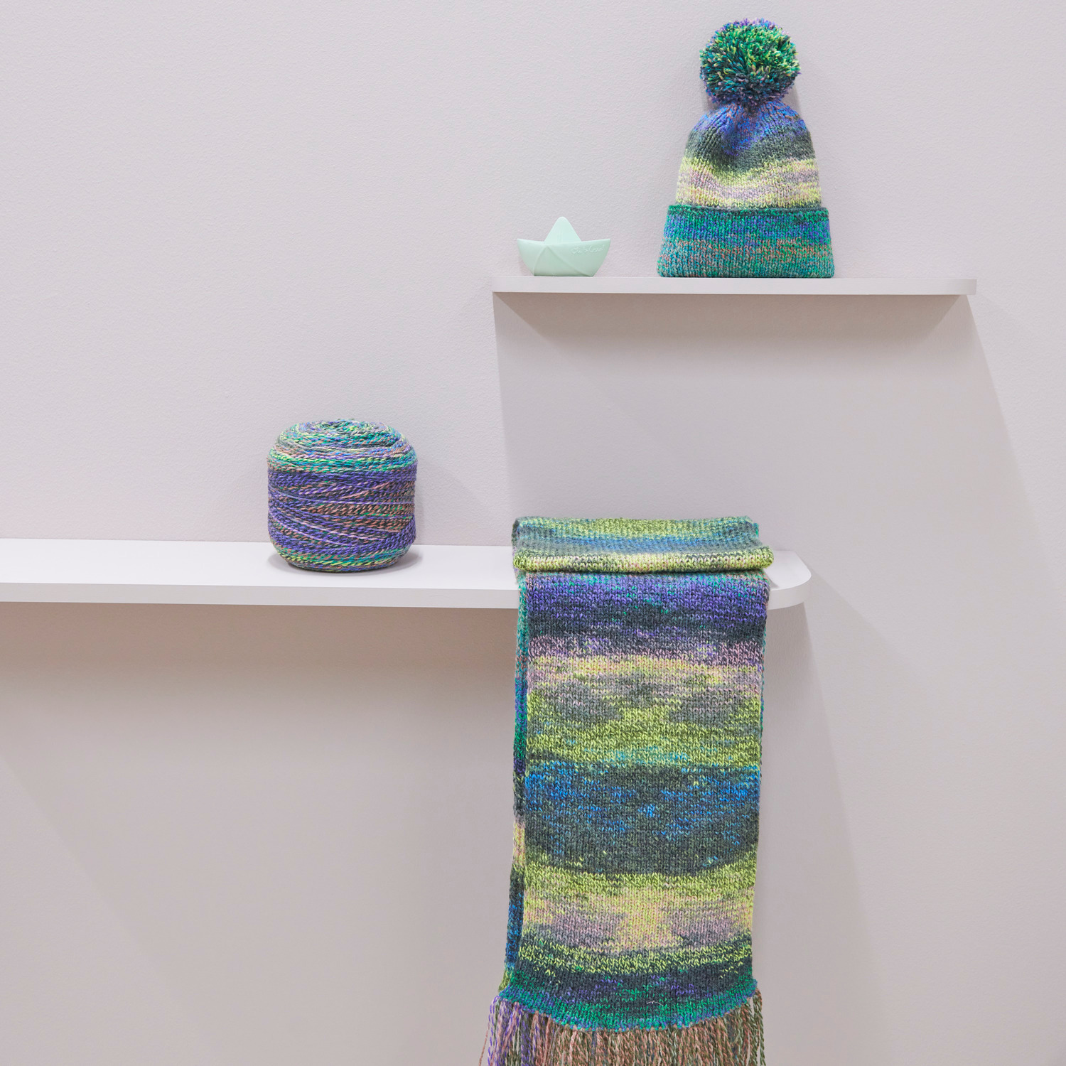 Rico Kids 13: Strickset mit Mütze und Schal in frischen Farben auf weißen Regalen präsentiert.