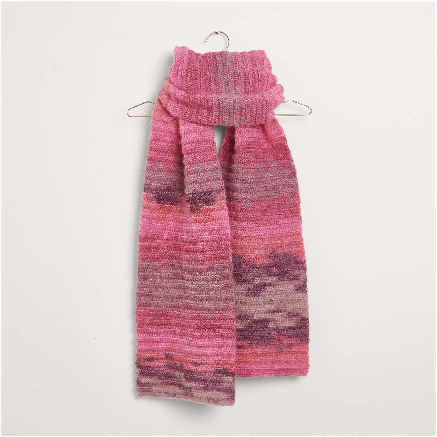Häkelset Schal Modell 09: Ein gestrickter Schal in Rosa- und Lilatönen, aufgehängt an einem Kleiderbügel.