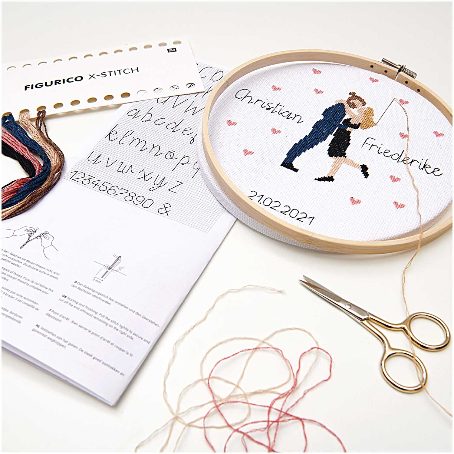 Figurico Stickpackung Lovebirds 20cm zeigt ein gesticktes Paar mit Herzmotiven und Garn in verschiedenen Farben.