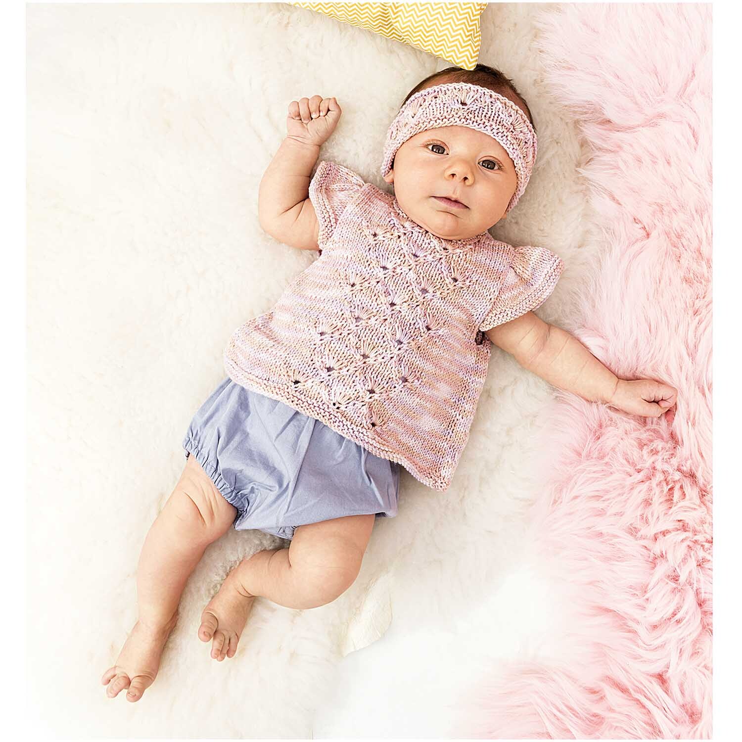 Rico Baby Cotton Soft Print dk: Ein Baby trägt ein gestricktes Outfit in Rosa und Lila von Rico Design.