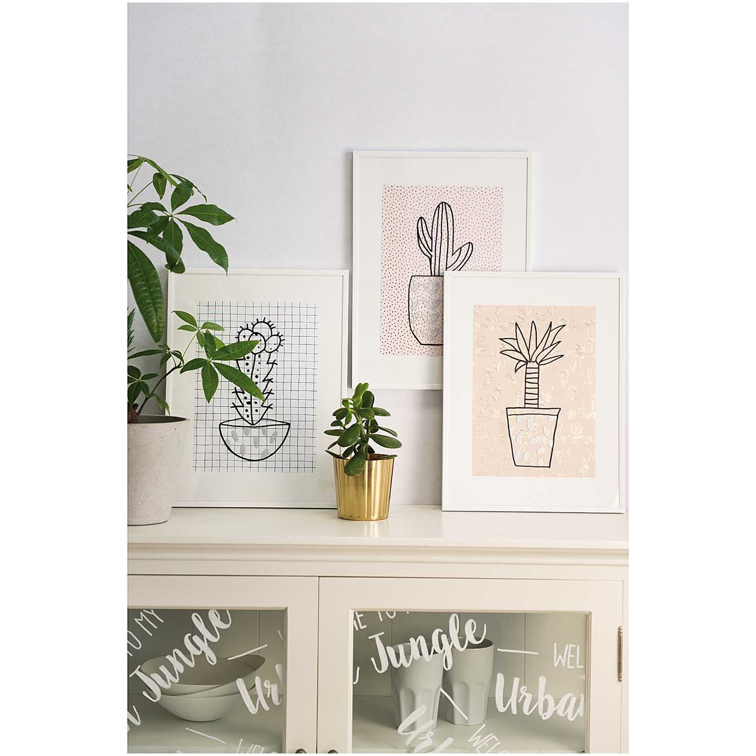 Vorlagenmappe Hygge Fenster- und Glasmalerei mit Kreidestiften zeigt Pflanzenbilder in weißen Rahmen auf einem Schrank.
