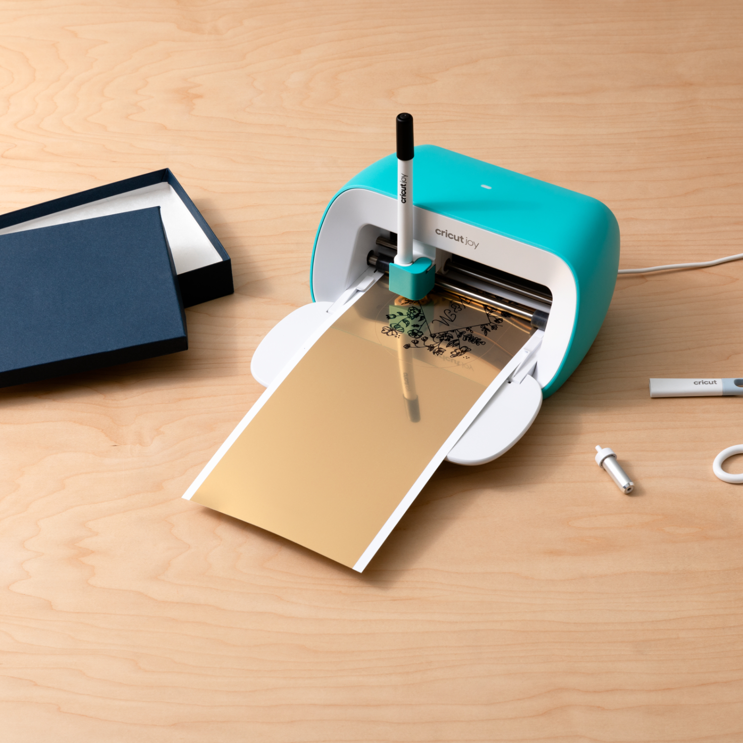 Joy Smart Vinyl Permanent Writable, gold, wird von einem Cricut-Gerät auf einem Holztisch bearbeitet.