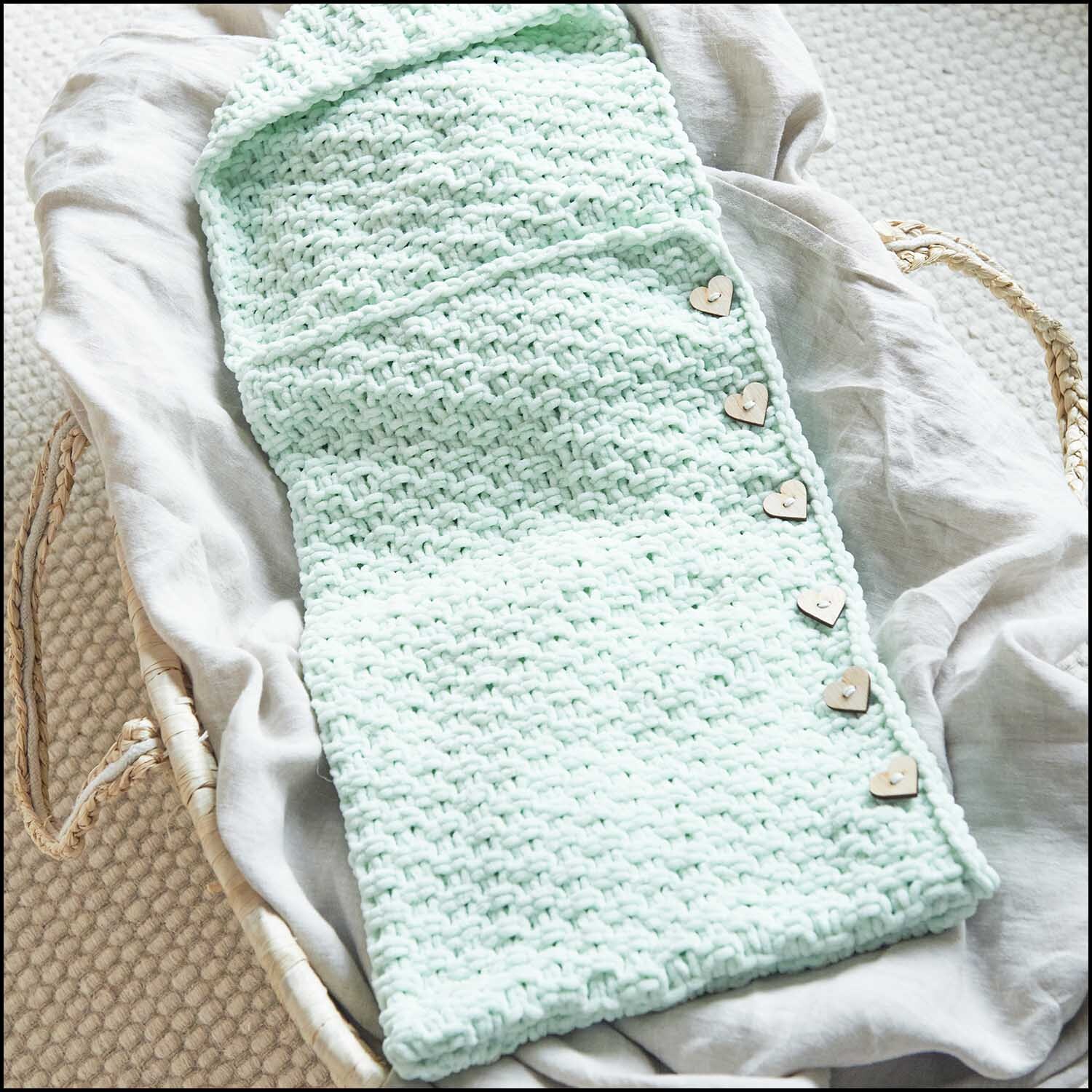 Holzknöpfe Herzen 4 Stück von Rico Design auf einem mintgrünen, gestrickten Stoffstück.