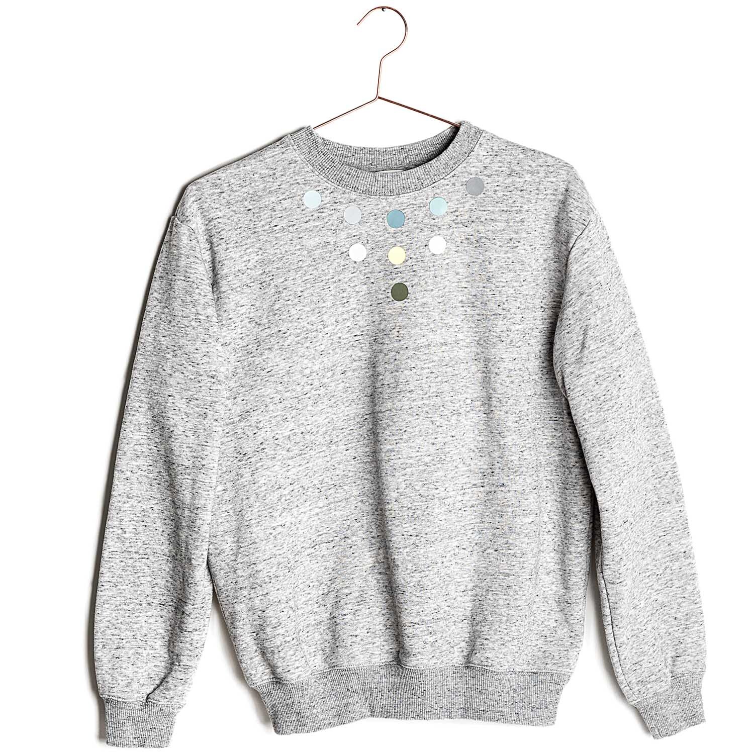 Bügelmotiv Kreise grün Mix 18 Stück auf grauem Pullover von Rico Design, dekorativ angeordnet.