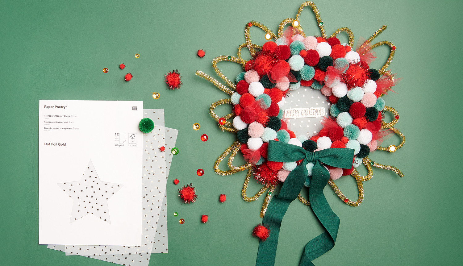 Bastelanleitung Weihnachtskranz mit Pompons: Bunter Kranz aus roten, weißen und grünen Pompons auf grünem Hintergrund mit Schleife und Bastelmaterial.
