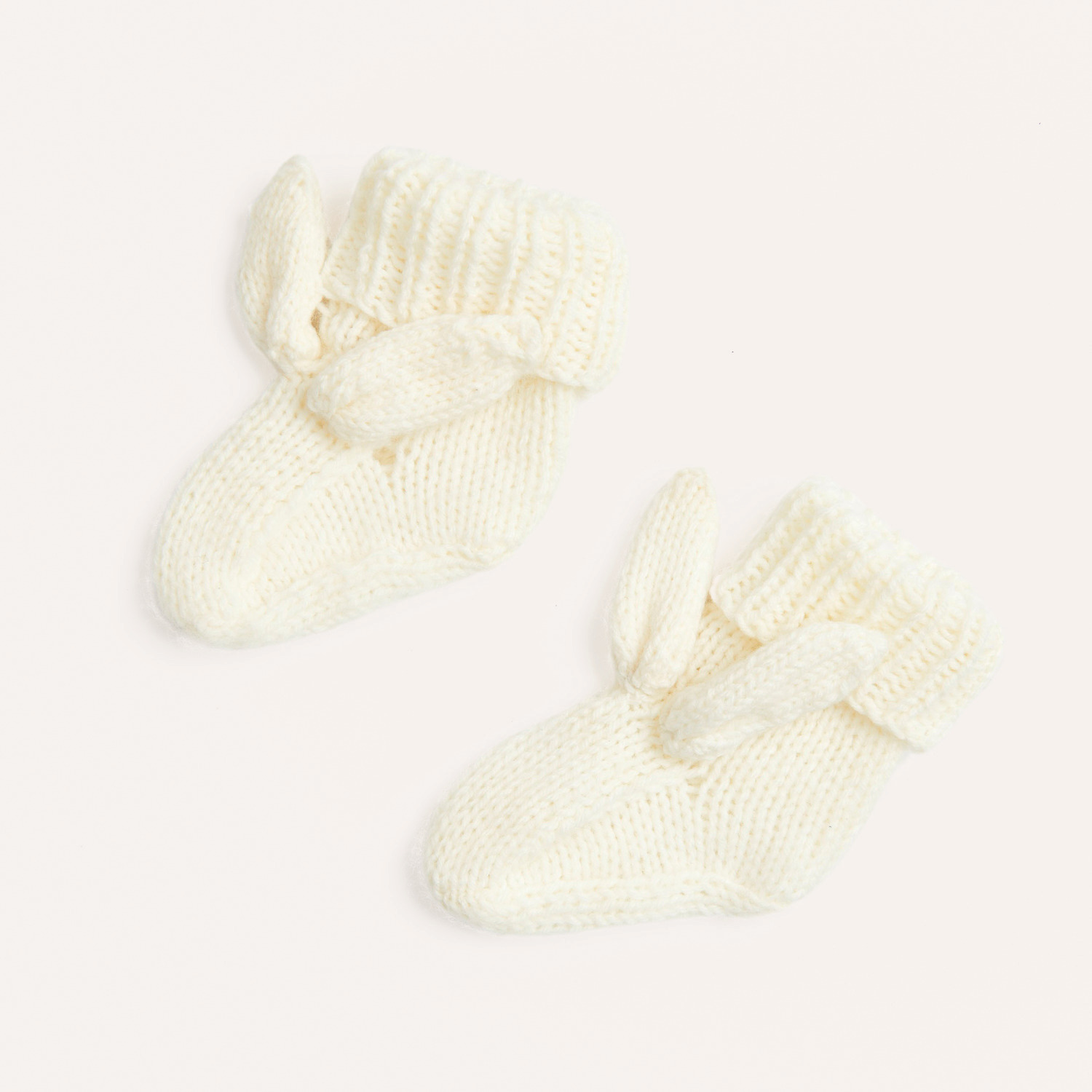Strickset Schühchen mit Häschenohren Modell 02 aus Rico Baby 040. Cremefarbene Babyschuhe mit niedlichen Ohren, ideal für Neugeborene.