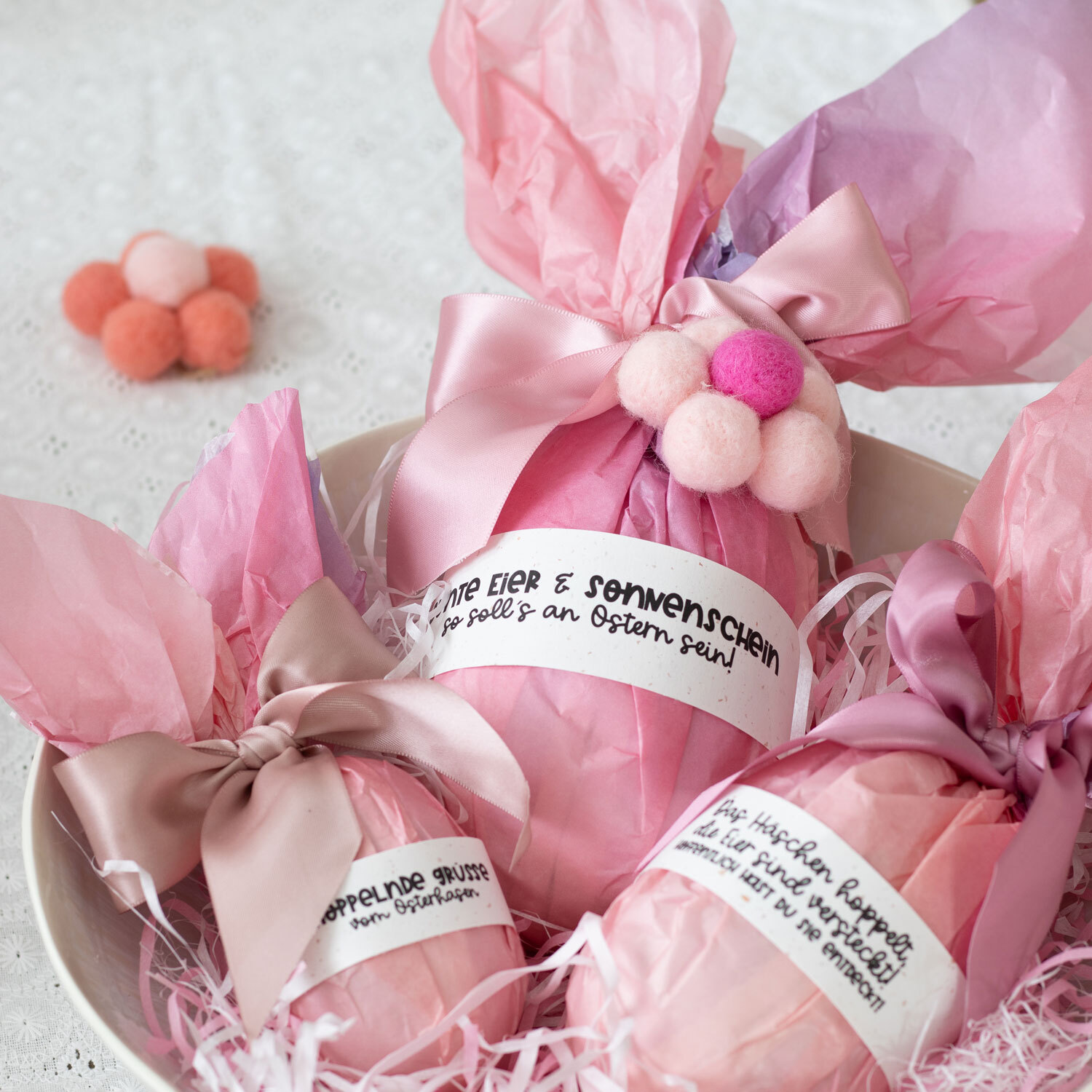 Inspiration Geschenkverpackung für Ostern: Rosa Verpackung mit Schleifen und Filzkugeln.
