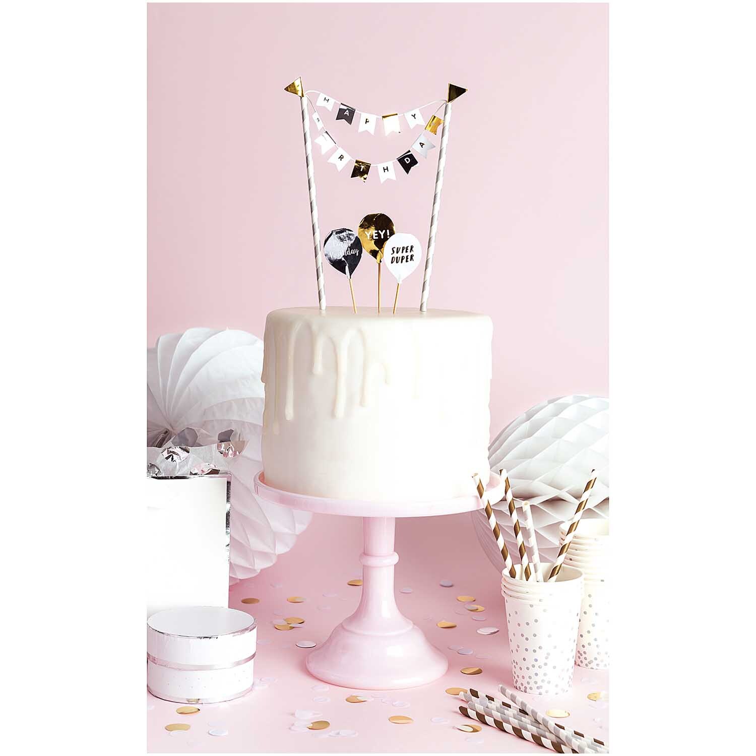 Kuchendekoration Happy Birthday classic auf weißem Kuchen mit rosa Hintergrund und Partydeko.