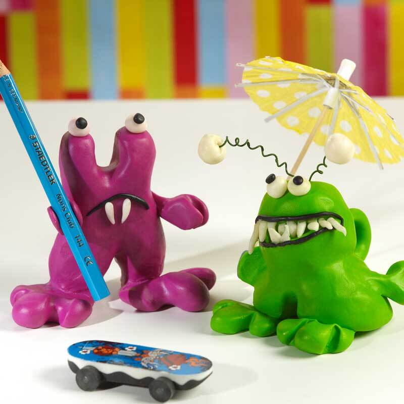 FIMO soft: Zwei bunte Knetfiguren, eine grüne mit Schirm und eine violette mit Stift, vor buntem Hintergrund.