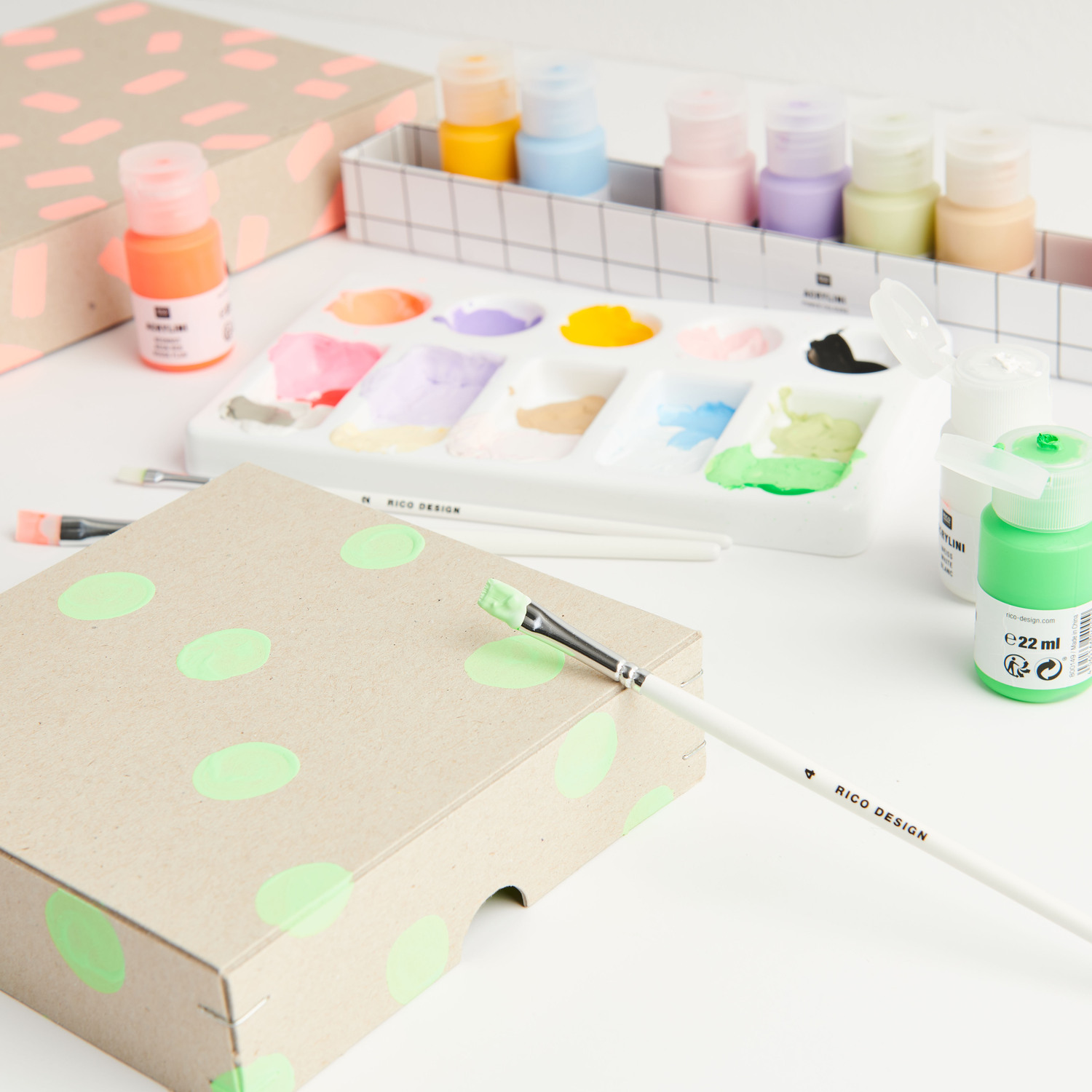 Acrylini Acrylfarben Set Power Colours mit 12x22ml Tuben, Pinseln und Mischpalette auf einem Tisch.