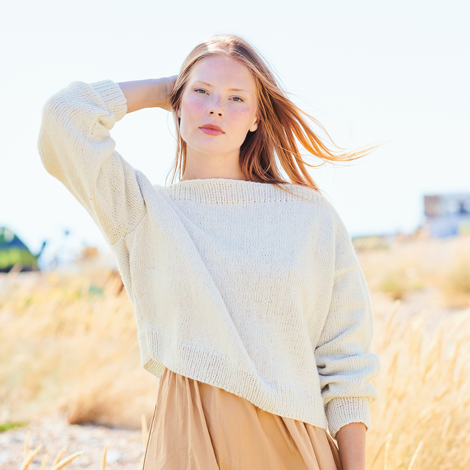 Strickanleitung Pullover aus Creative Cotton Fleece dk: Frau trägt cremefarbenen Pullover in natürlicher Umgebung.