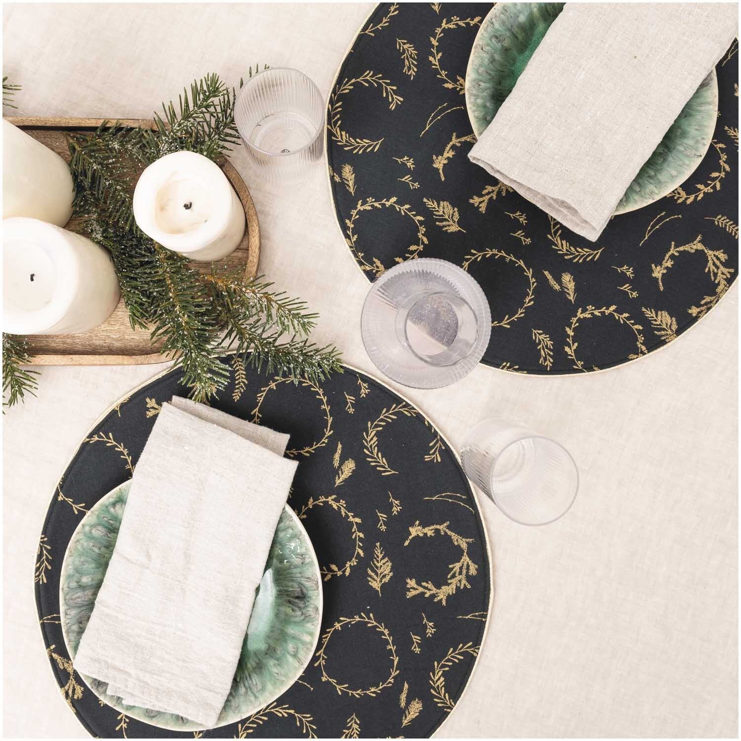 Druckstoff Nostalgic Christmas Kränze zeigt elegante Tischdekoration mit schwarzen und goldenen Kränzen auf runden Platzdeckchen.