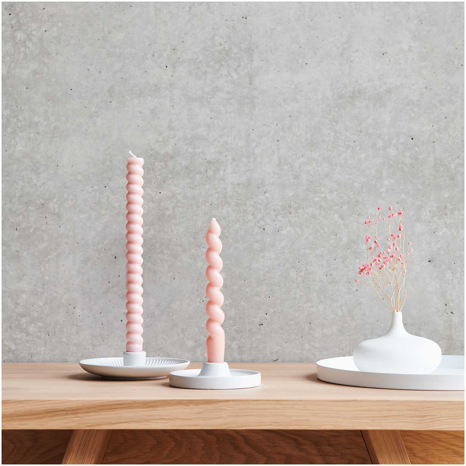Keramikkerzenhalter von Rico Design auf Holztisch, mit rosa Kerzen und weißer Vase vor Betonwand.