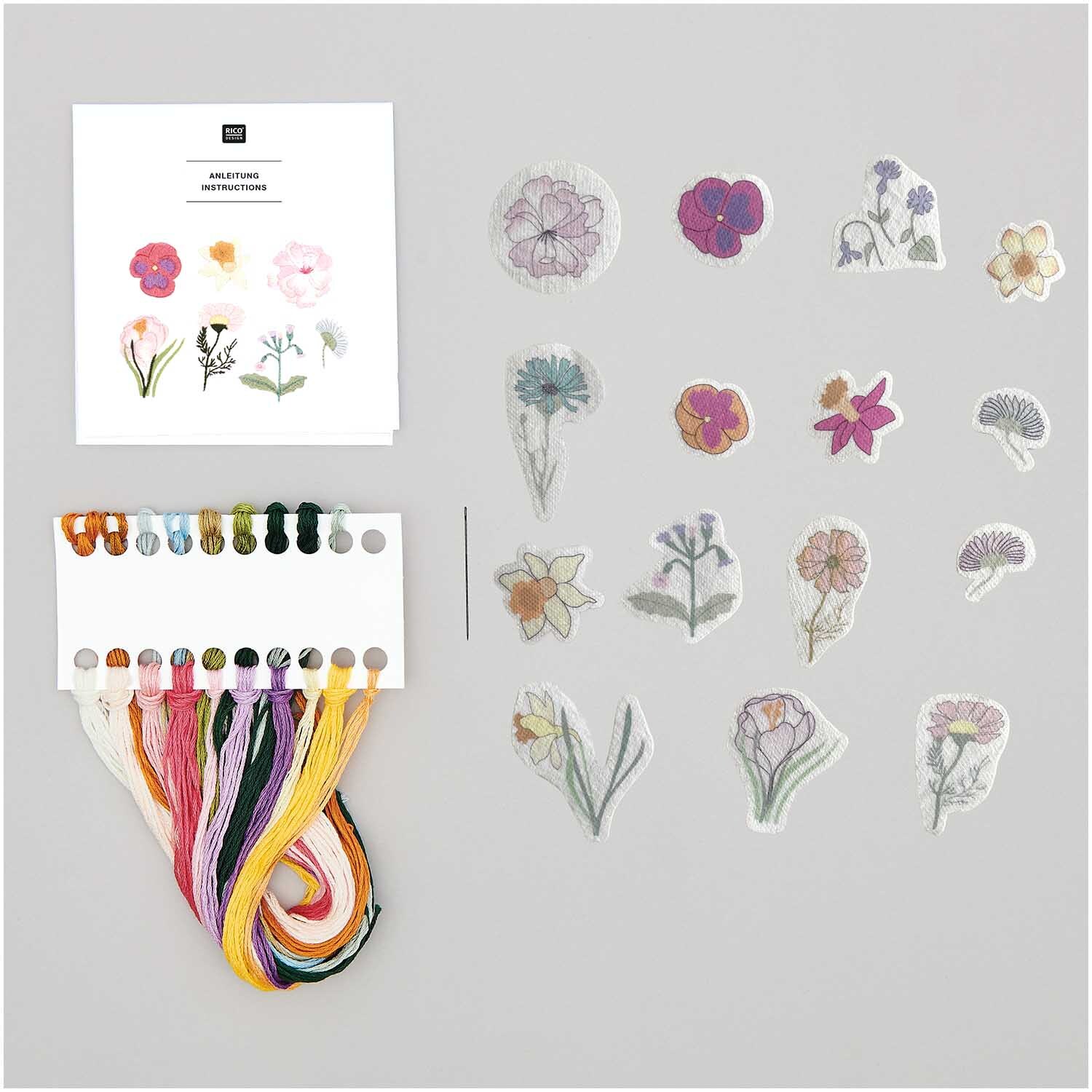 Stick and Stitch Stickpackung Frühlingsblumen mit 15 vorgezeichneten Motiven und bunten Garnen von Rico Design auf grauem Hintergrund.