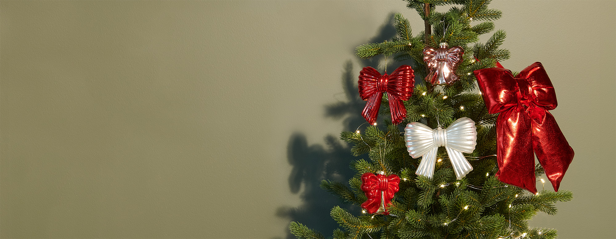 Ein Tannenbaum mit fünf verschiedenen Schleifenanhängern in rot und weiß.