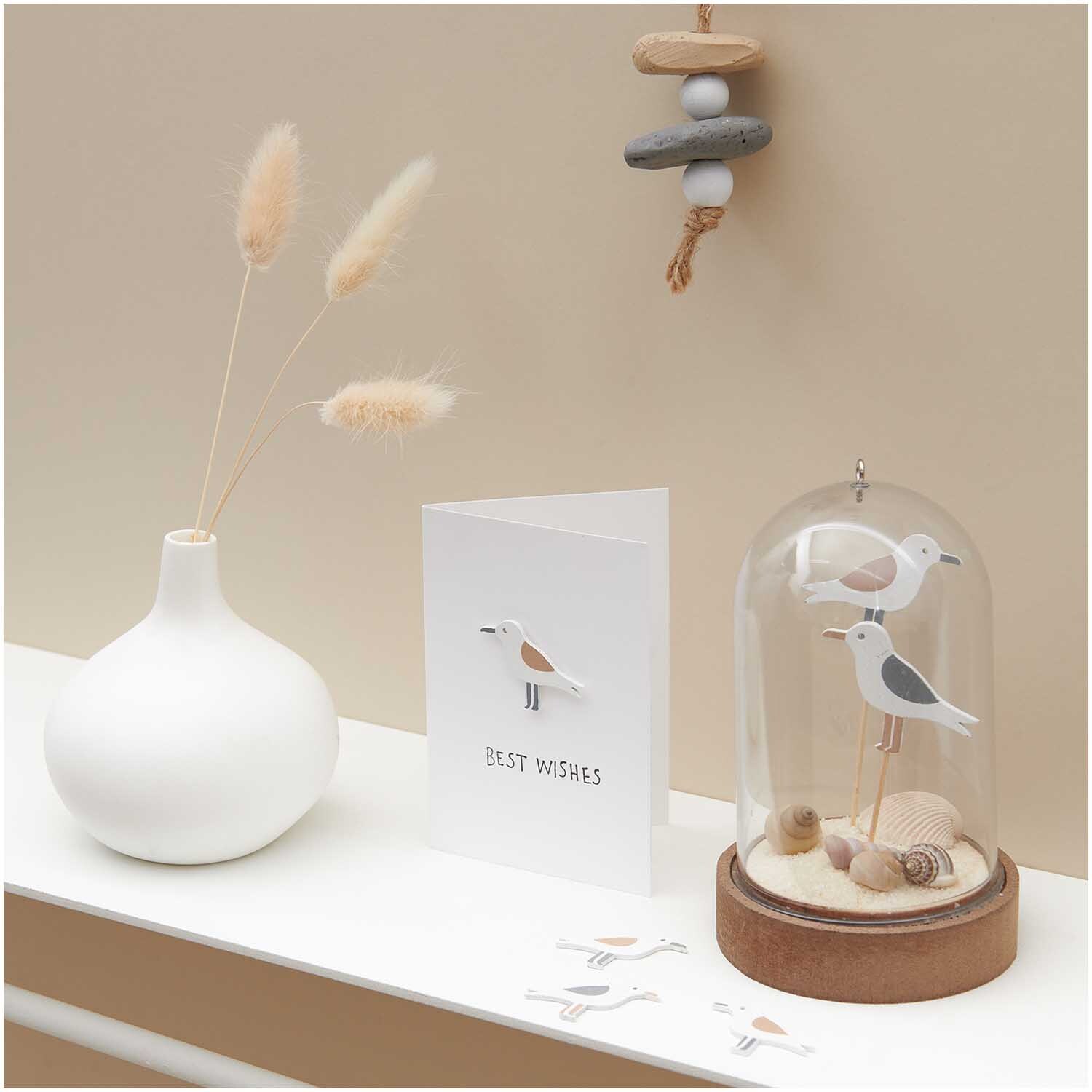Holzsticker Möwe natur 35x26mm 24 Stück von Rico Design, dekorativ arrangiert mit Muscheln und einer Karte auf einem Tisch.
