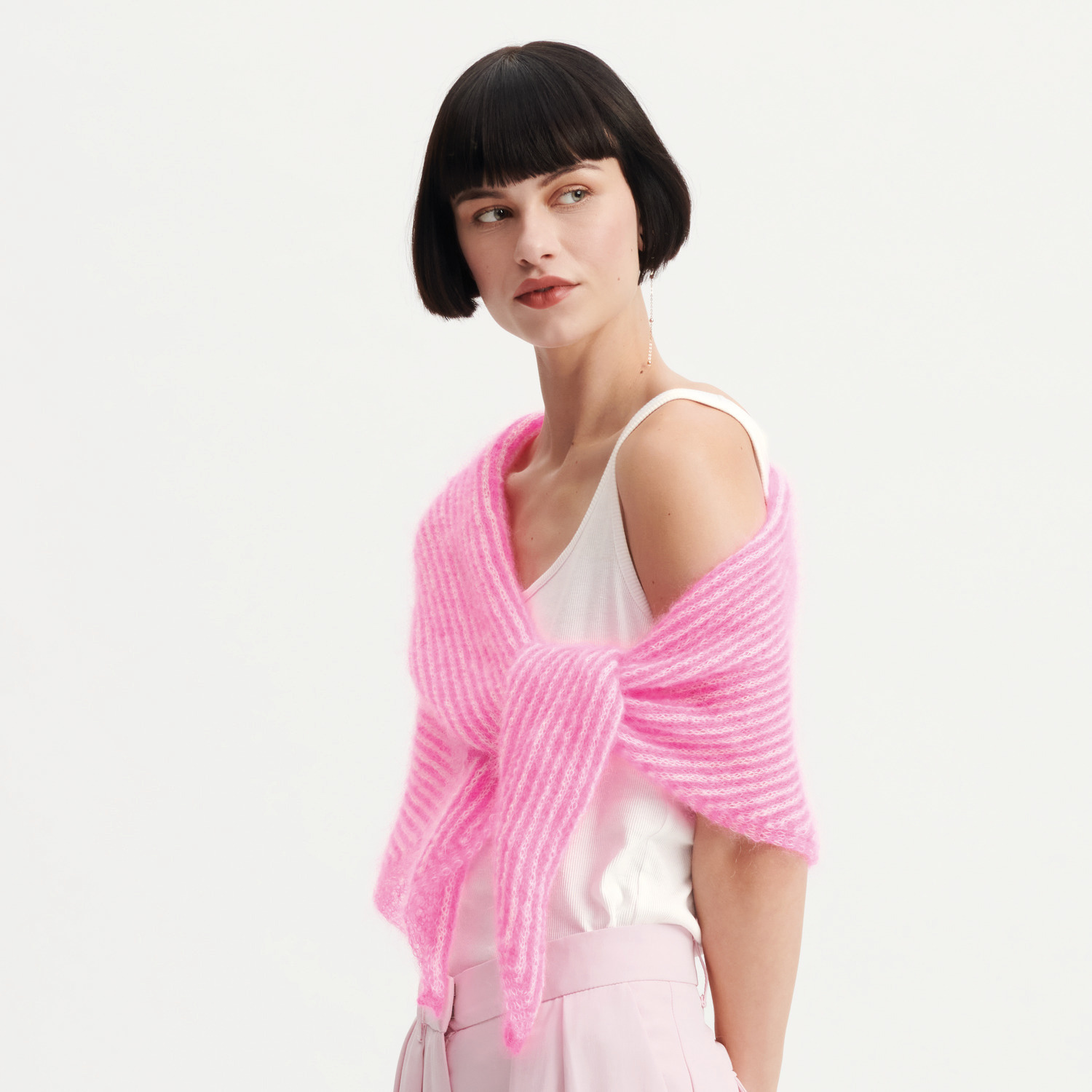 Strickset Dreieckstuch Modell 33: Frau trägt ein rosa Dreieckstuch über einem weißen Top.