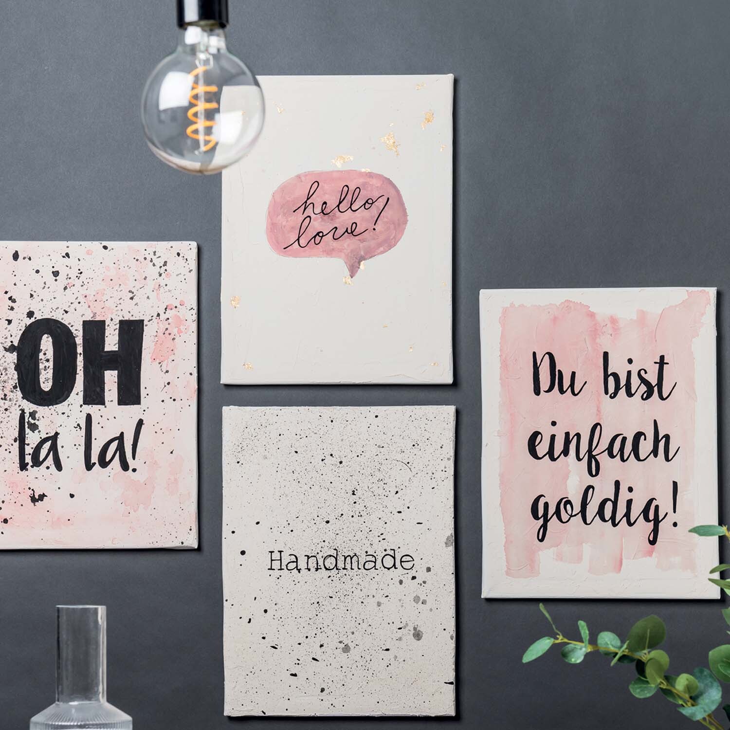 Anleitung Bilder mit Strukturpaste gestalten: Vier Leinwände mit Sprüchen und Strukturpaste, dekorativ an einer Wand arrangiert.