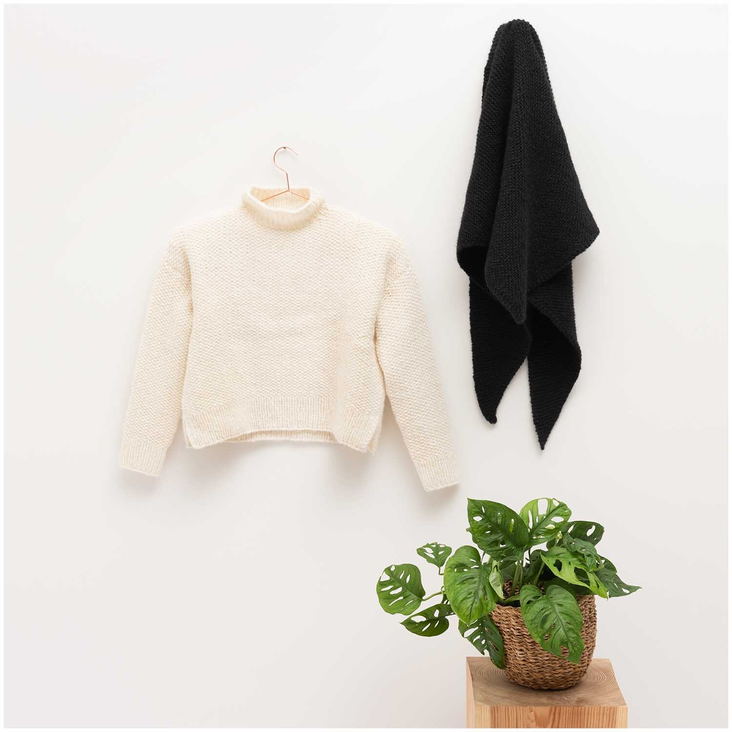 Luxury Baby Alpaca & Merino chunky - Madly in Love: Cremefarbener Pullover und schwarzer Schal von Rico Design, dekoriert mit einer Pflanze.