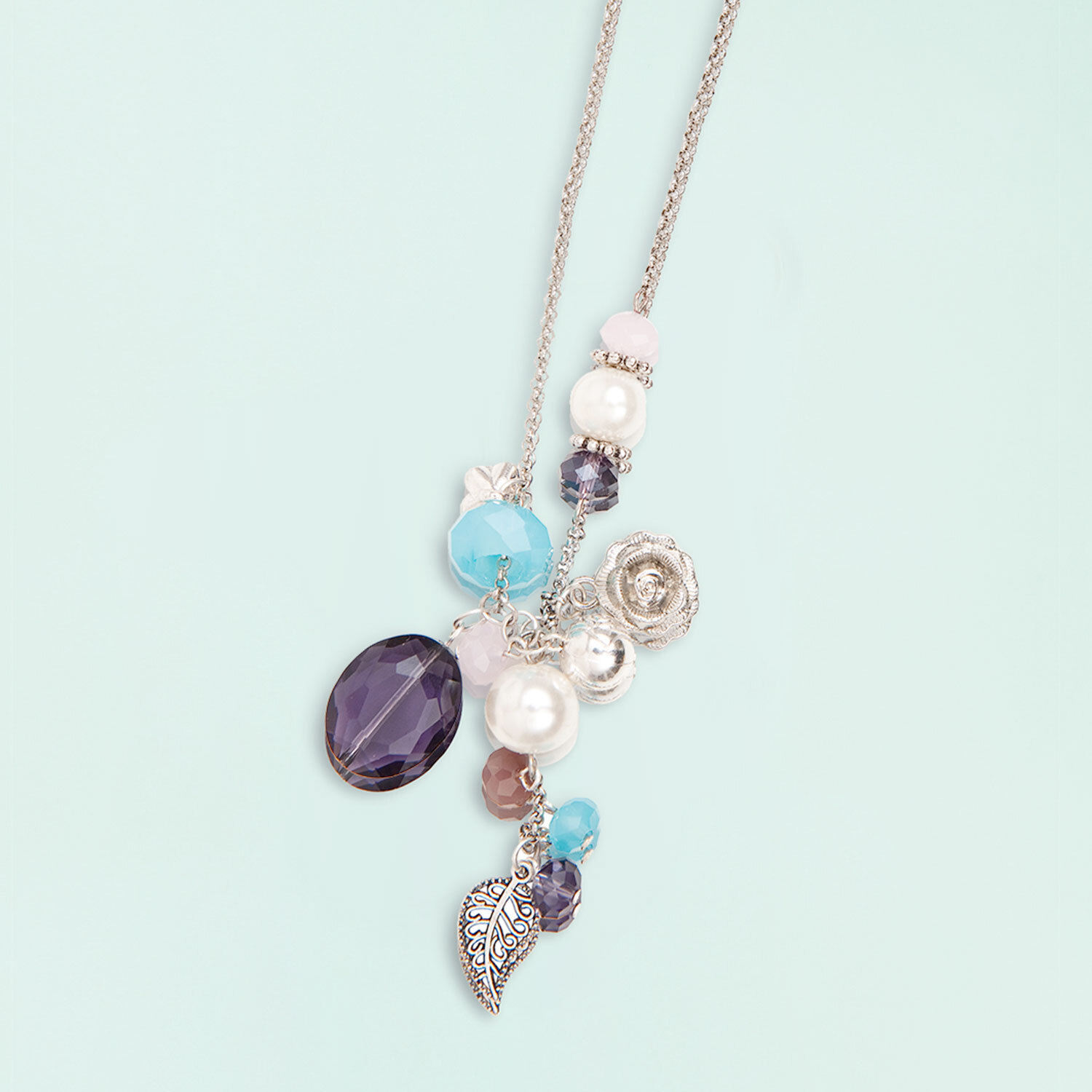 Anleitung Perlenset Fashion Kette basteln: Elegante Kette mit bunten Perlen und silbernen Anhängern auf hellblauem Hintergrund.