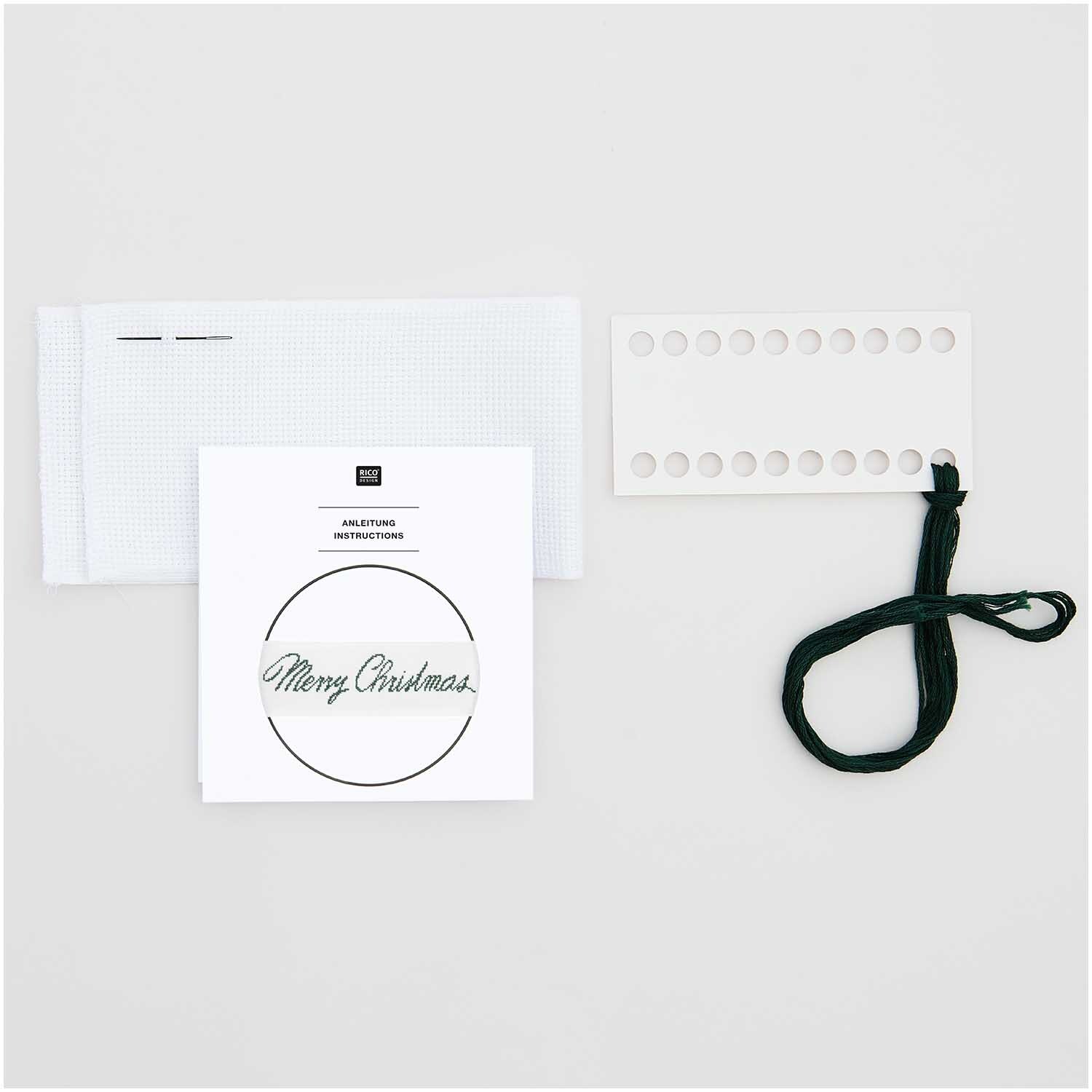 Stickpackung Band Frohe Weihnachten von Rico Design mit weißem Stoff, Anleitung und schwarzem Faden.