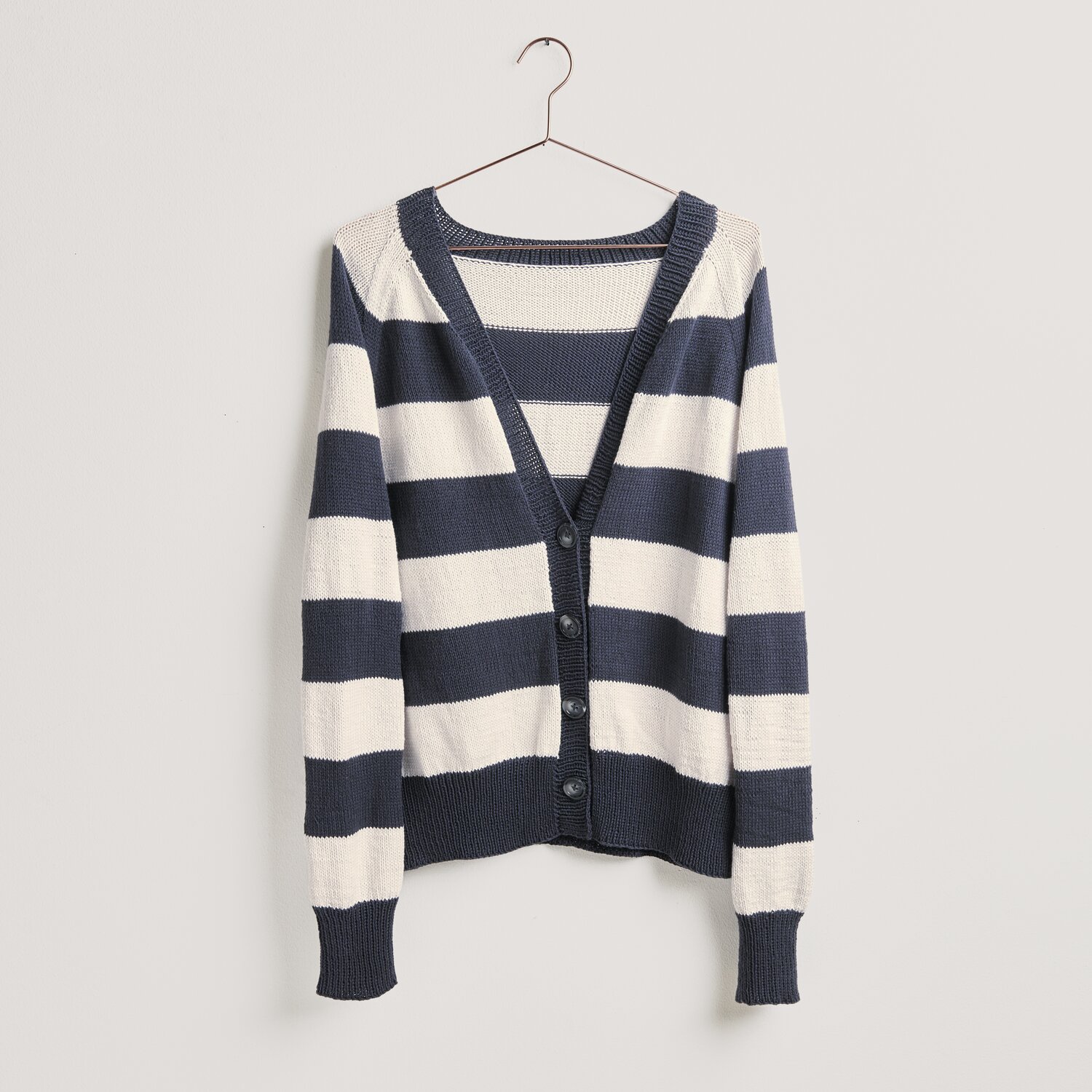 Strickset Jacke Modell 07: Gestreifte Jacke in Weiß und Marine von Rico Design, hängend an einem Kleiderbügel. Ideal für Frühjahr-Sommer.