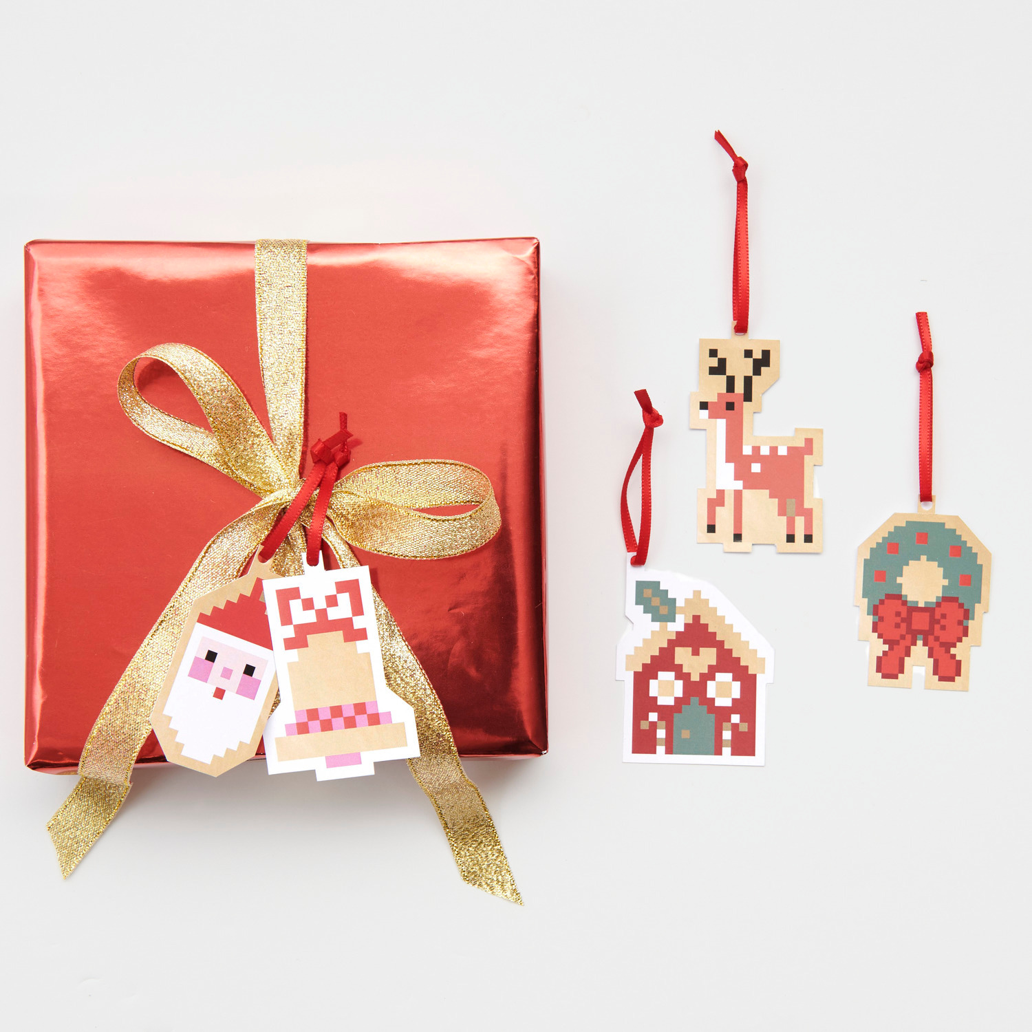 Paper Poetry Geschenkanhänger S Figuren Pixel: Rotes Geschenk mit goldener Schleife und pixeligen Anhängern in Tier- und Weihnachtsmotiven.
