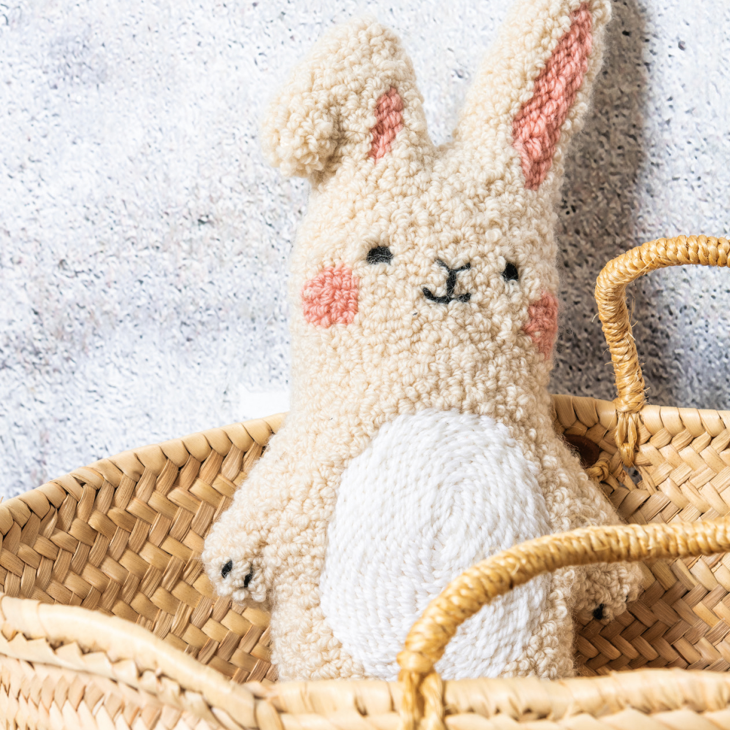 Punch Needle Anleitung Hase: Flauschiger Hase aus Punch Needle in einem Korb, mit rosa Wangen und Ohren.