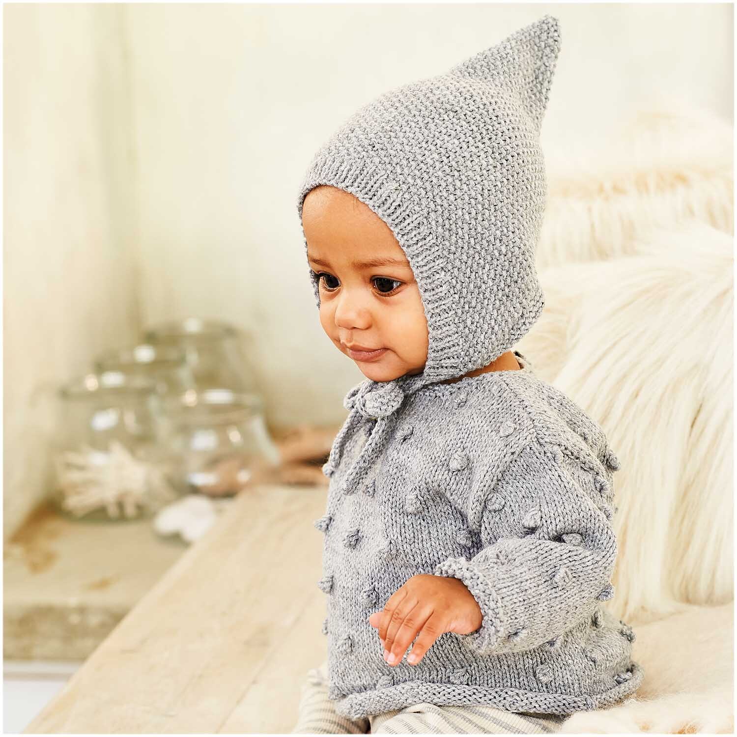 Rico Baby Classic dk: Ein Baby trägt einen gestrickten Anzug und Mütze in Silber Melange. Ideal für weiche, bequeme Babykleidung.