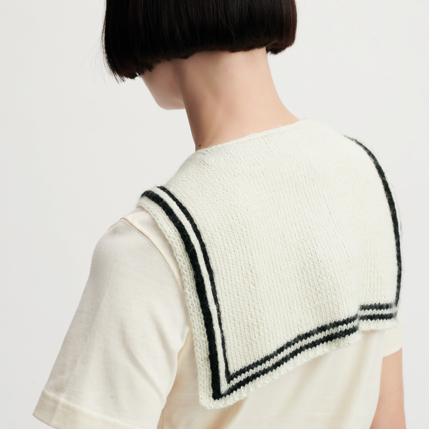 Creative Cotton Fleece dk Strickset zeigt ein gestricktes Tuch in Offwhite mit schwarzen Streifen, getragen von einer Person.
