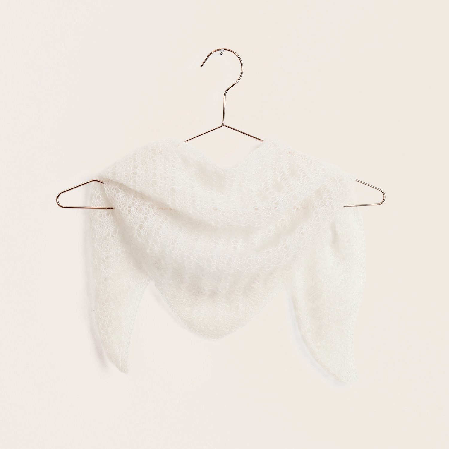 Strickset Dreieckstuch Modell 08 aus Trachtenbuch I mog di, weiß, aus Essentials Super Kid Mohair Loves Silk, hängt auf einem Kleiderbügel.