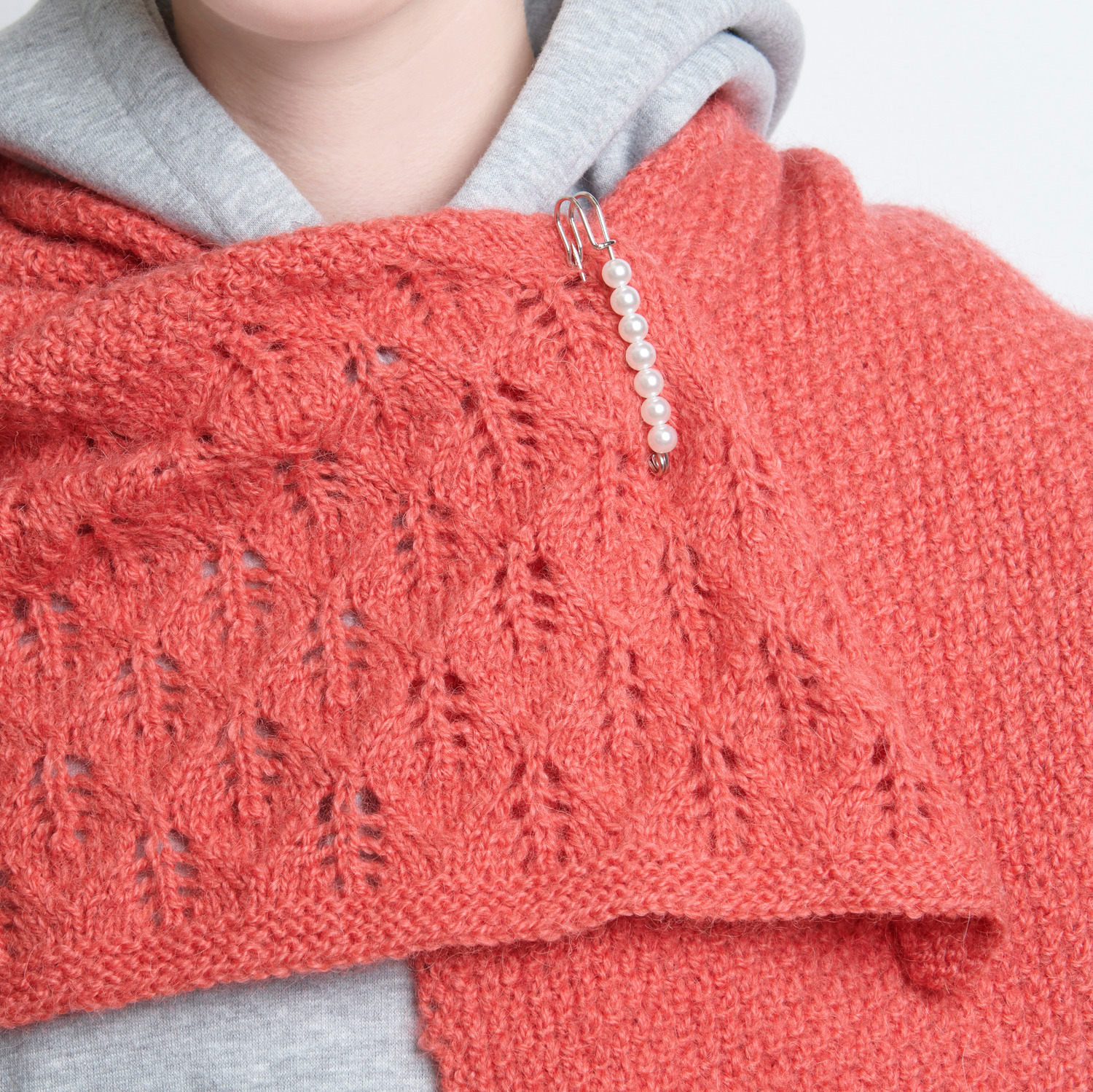 Kiltnadel mit Perlen an einem roten Strickschal, verziert mit silbernen Details von Rico Design.