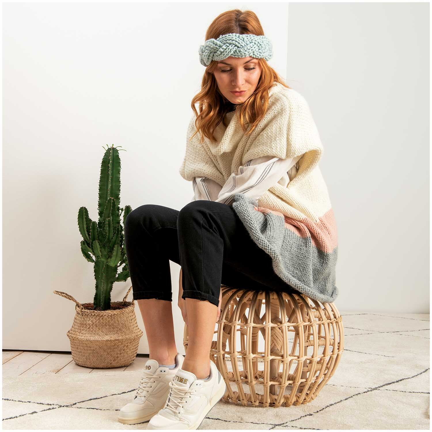 Essentials Mega Wool chunky: Frau mit gestricktem Stirnband in Mint, sitzt auf Korbhocker neben Kaktus.