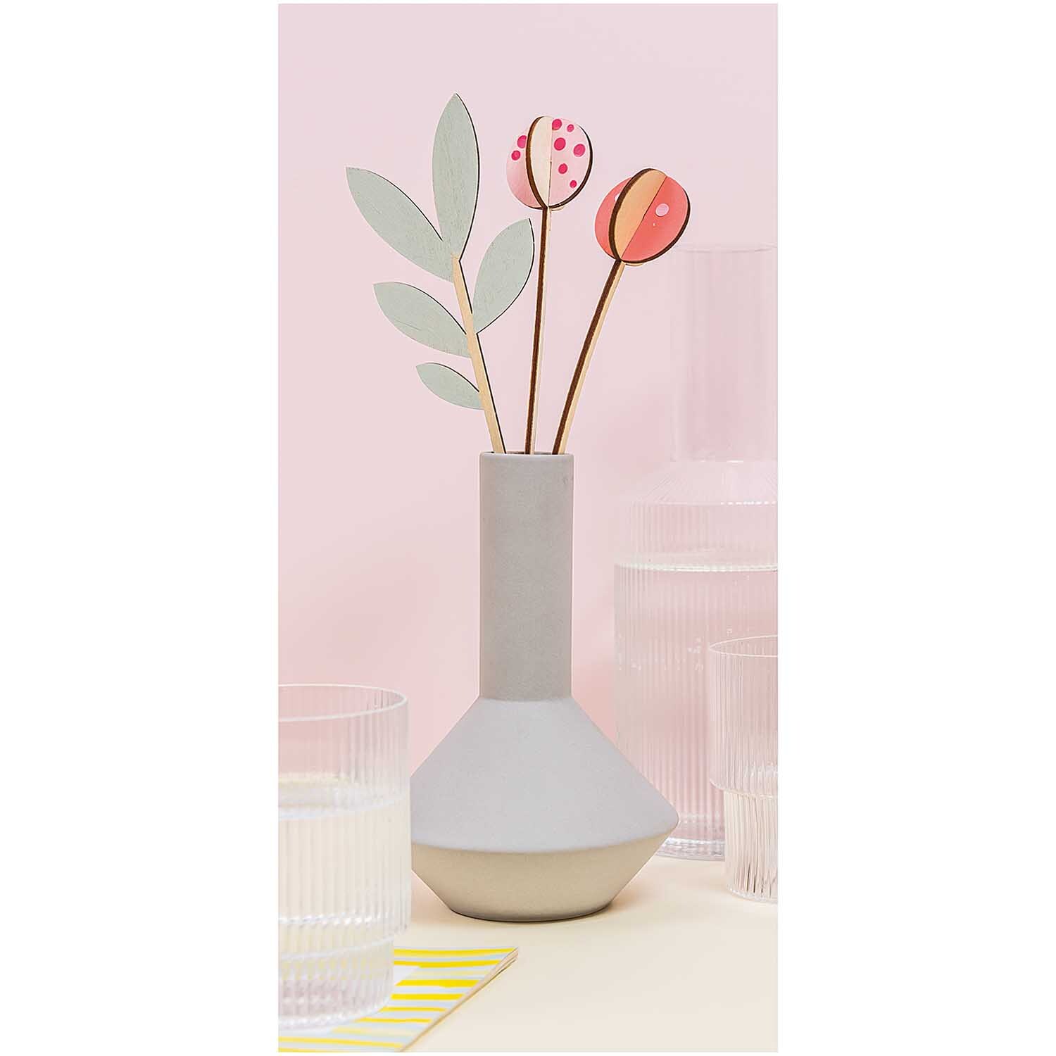 Stecktulpen 28cm 2 Stück in einer grauen Vase, umgeben von transparenten Gläsern auf hellem Tisch.