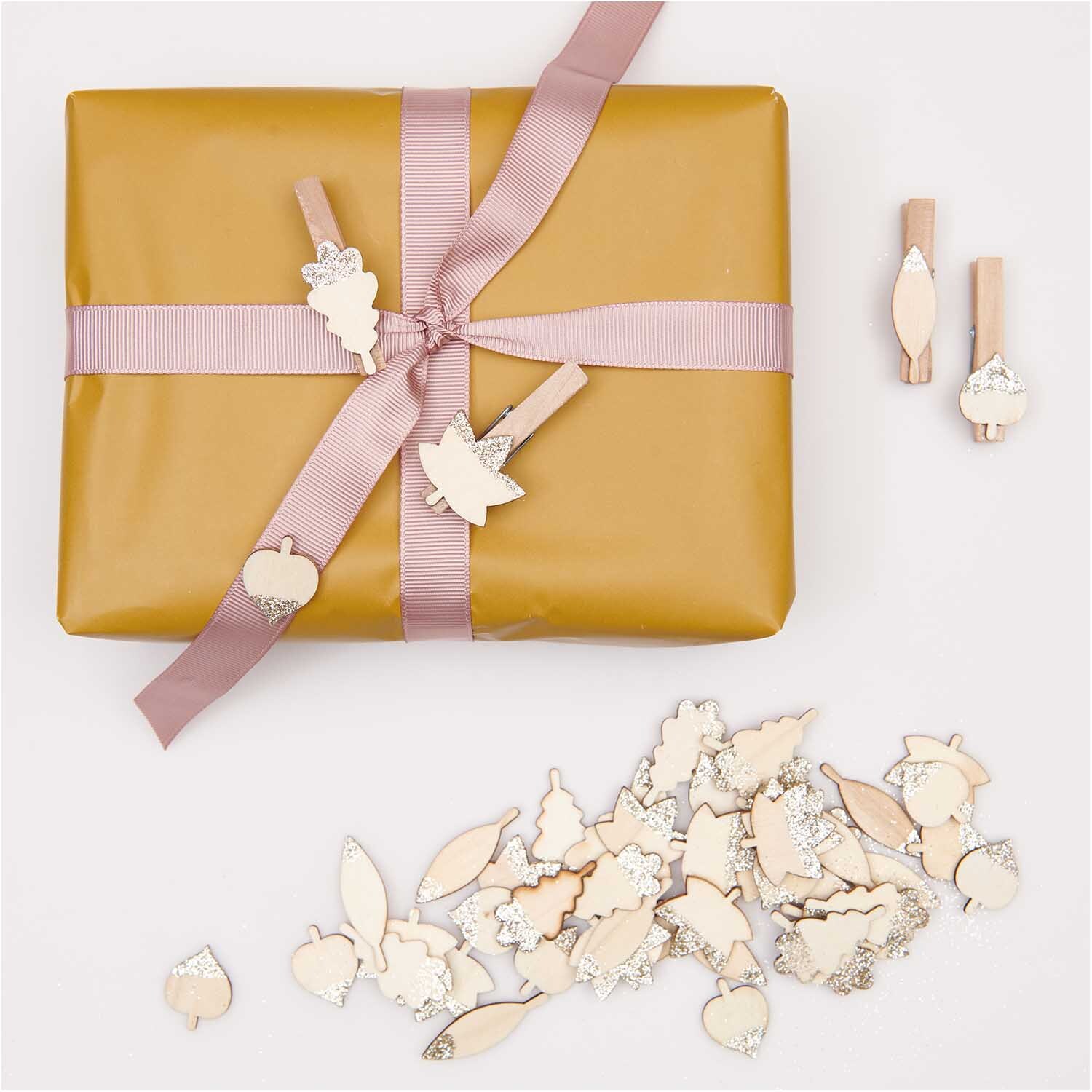 Holzsticker Blätter Mix mit Glitter natur-gold, dekorativ auf Geschenk mit rosa Band arrangiert.