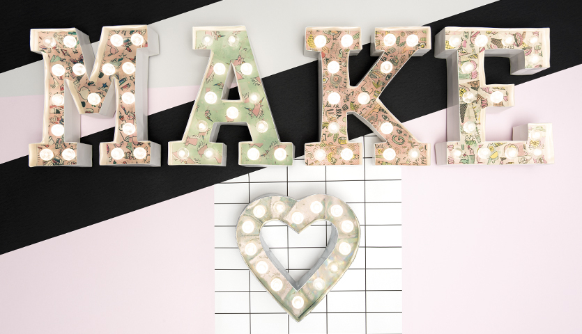 Bastelanleitung LED-Leuchtbuchstaben gestalten: Buchstaben "MAKE" mit LED-Lichtern auf pastellfarbenem Hintergrund.